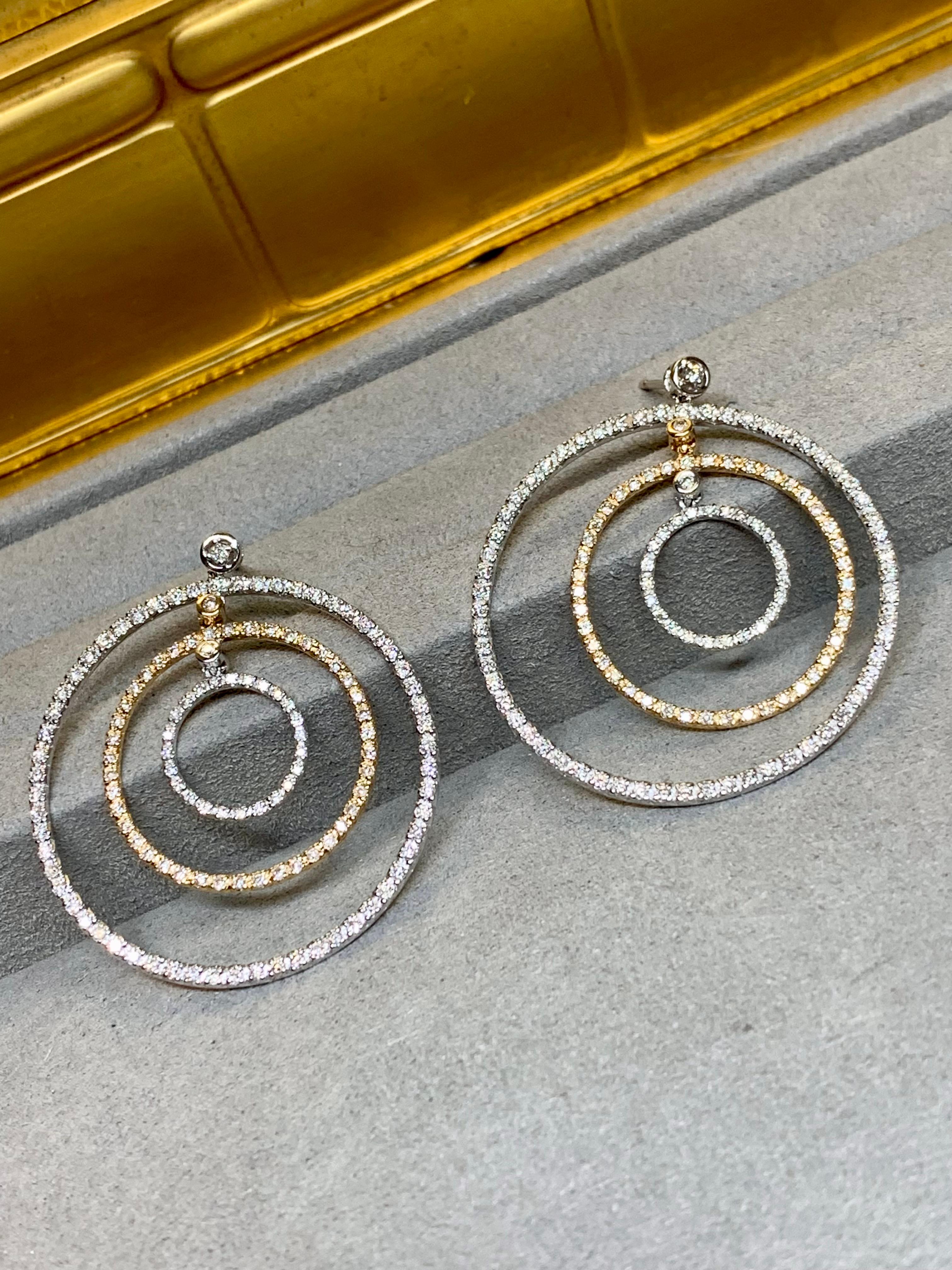 
A stylish and contemporary pair of circular drop earrings crafted in 14 karat yellow and white gold. Each earring features a trio of individually suspended circles: the largest outer circle in white gold, a slightly smaller yellow gold circle