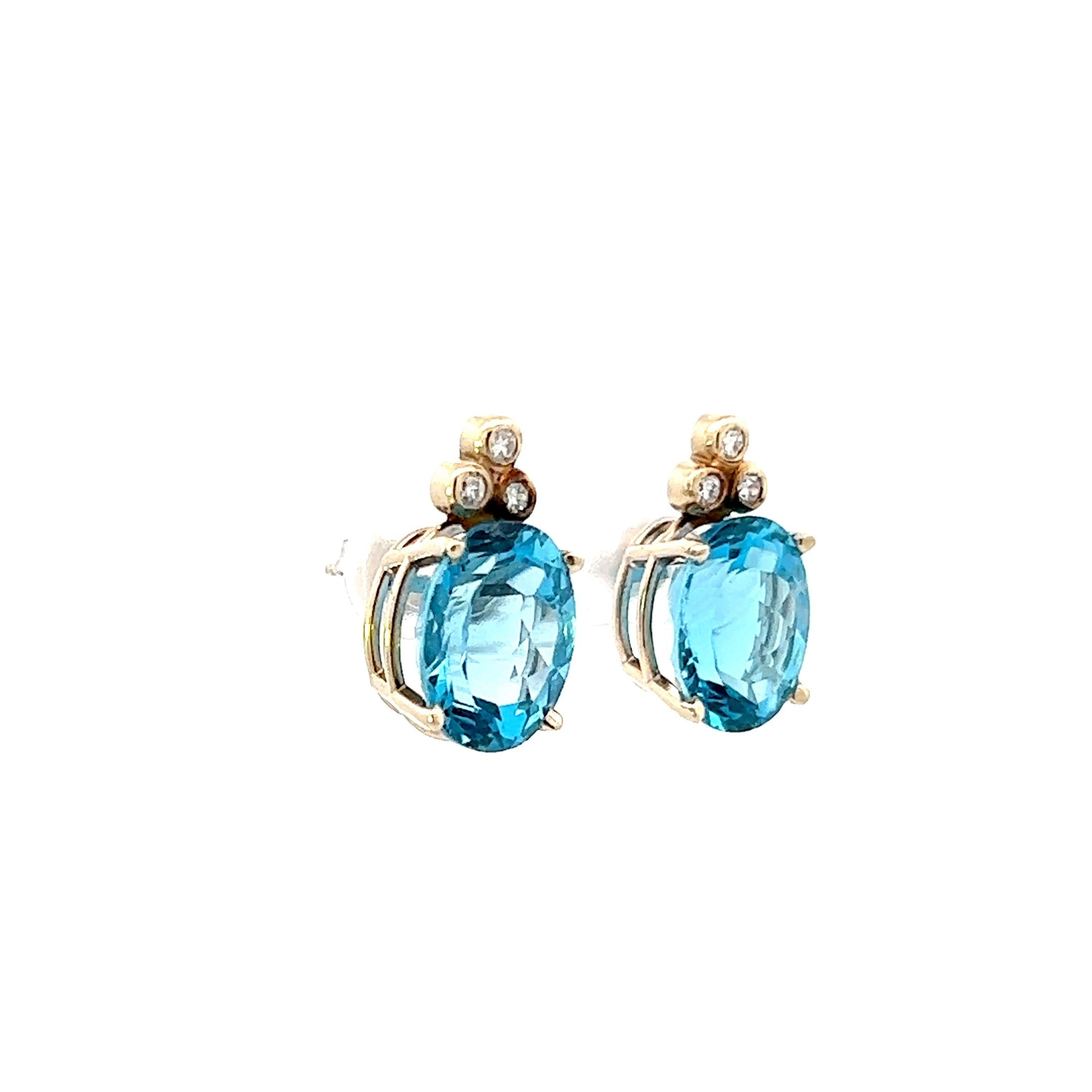 This is a beautiful pair of contemporary earrings made in 14k yellow gold and featuring both soft sky blue topaz and white firey diamond. Each individual earring features three round cut, Si1 clarity, H color diamonds as well as a large 6 ct, oval