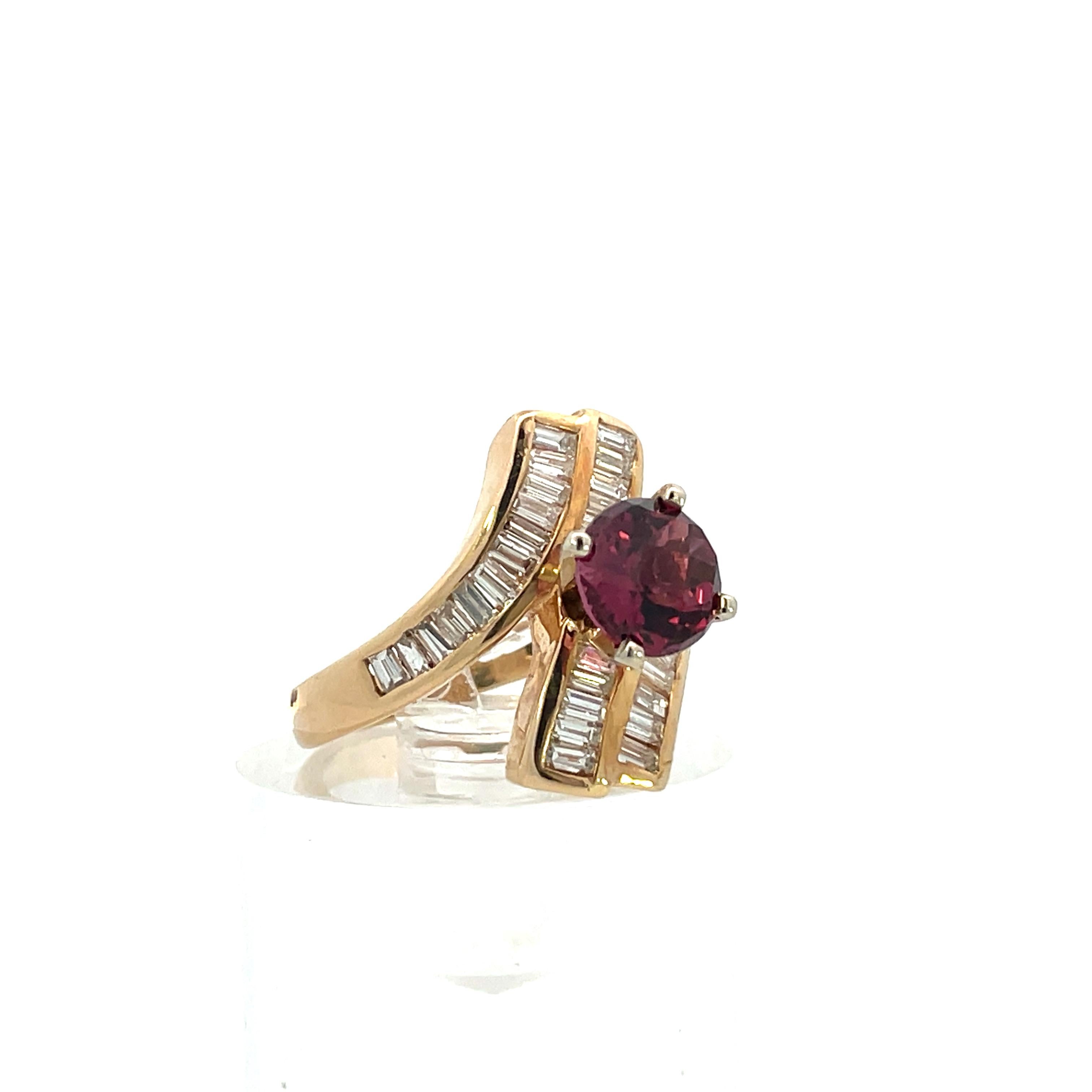 This is a beautiful contemporary ring, made in 14k yellow gold, featuring a red garnet with white baguette diamonds. The ring features three total bands, all showcasing 33 - G/H color VS2 baguette diamonds. The two outer bands passing the center of