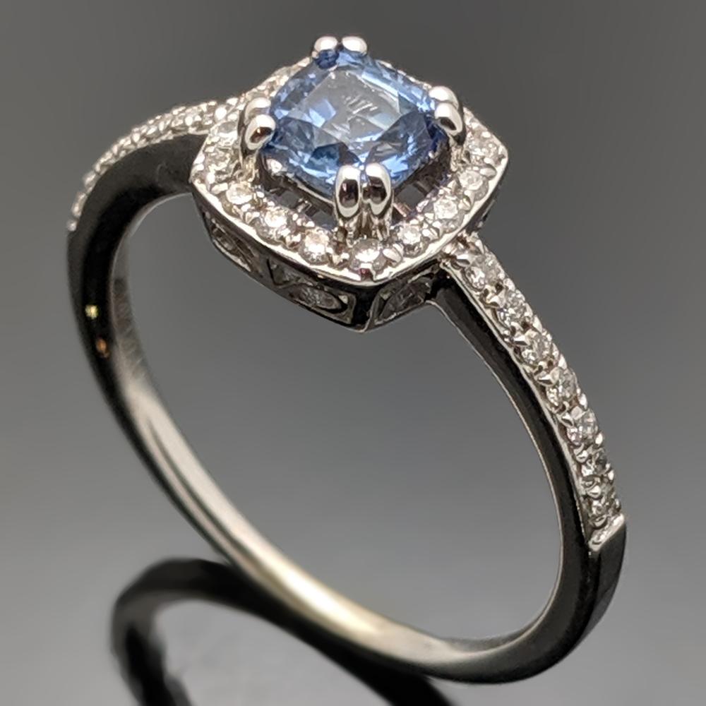 This ring is 14kt white gold with a blue sapphire at an estimated weight of 0.62ct. The halo and accents stones are diamonds estimated at 0.18cttw. 
Estimated weight of gold is 1.5 gr. 

We will size it for you.

