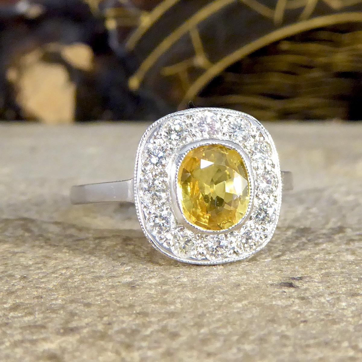 A bright and beautiful Contemporary cluster ring that will bring a splash of colour to any palette. It dazzles on the hand with a deep Yellow Sapphire featuring in the centre weighing 1.50ct in a bezel setting. The Yellow Sapphire is surrounded by a