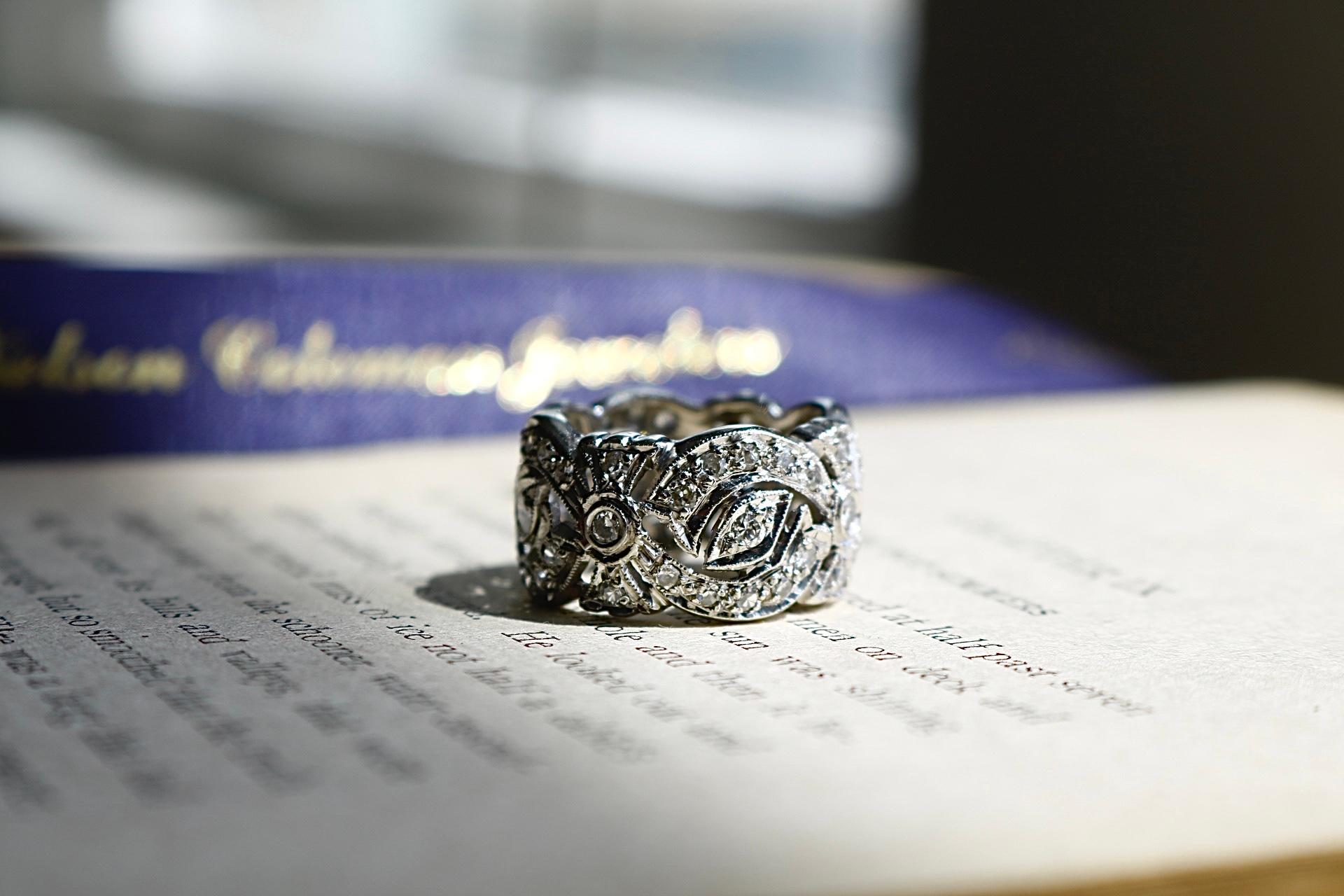 Crafted in 14 karat white gold, this contemporary openwork band showcases intricate milgrain detailing and a graceful, lace-like silhouette. Set with fifty-six round brilliant and single cut diamonds totaling approximately 1.62 carats, the diamonds