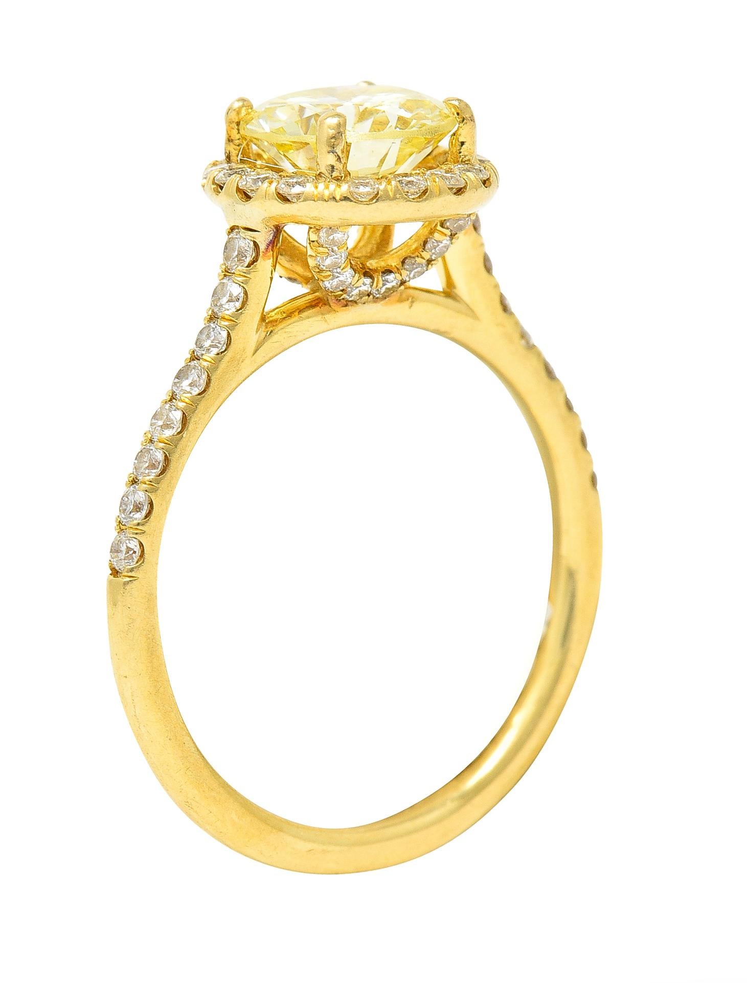 Centering a round brilliant cut diamond weighing 1.09 carats total. Natural fancy light yellow in color with VS2 clarity - prong set. Accented by recessed halo surround and cathedral shoulders. Featuring prong set round brilliant cut diamonds