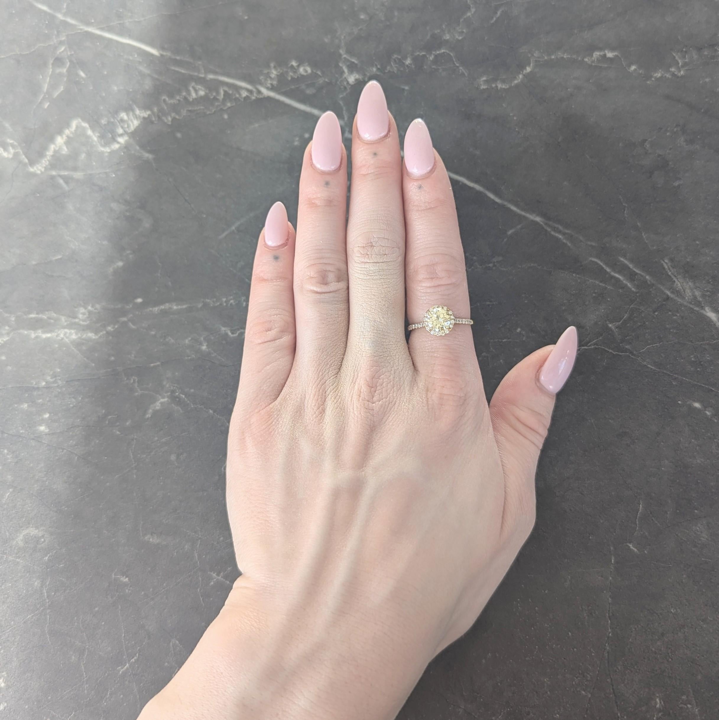 Centering a round brilliant cut diamond weighing 1.09 carats total
Natural fancy light yellow in color with VS2 clarity - prong set
Accented by recessed halo surround and cathedral shoulders
Featuring prong set round brilliant cut diamonds