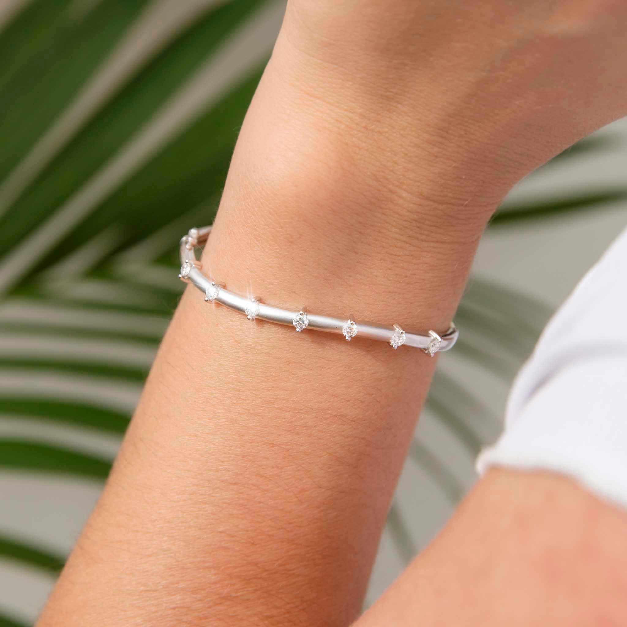Forged in 18 carat white gold, this graceful contemporary hinged bangle features eight shimmering round brilliant diamonds across the front half, each set between minimalist bars. We have named her The Soleil Bangle. She is a fabulously elegant