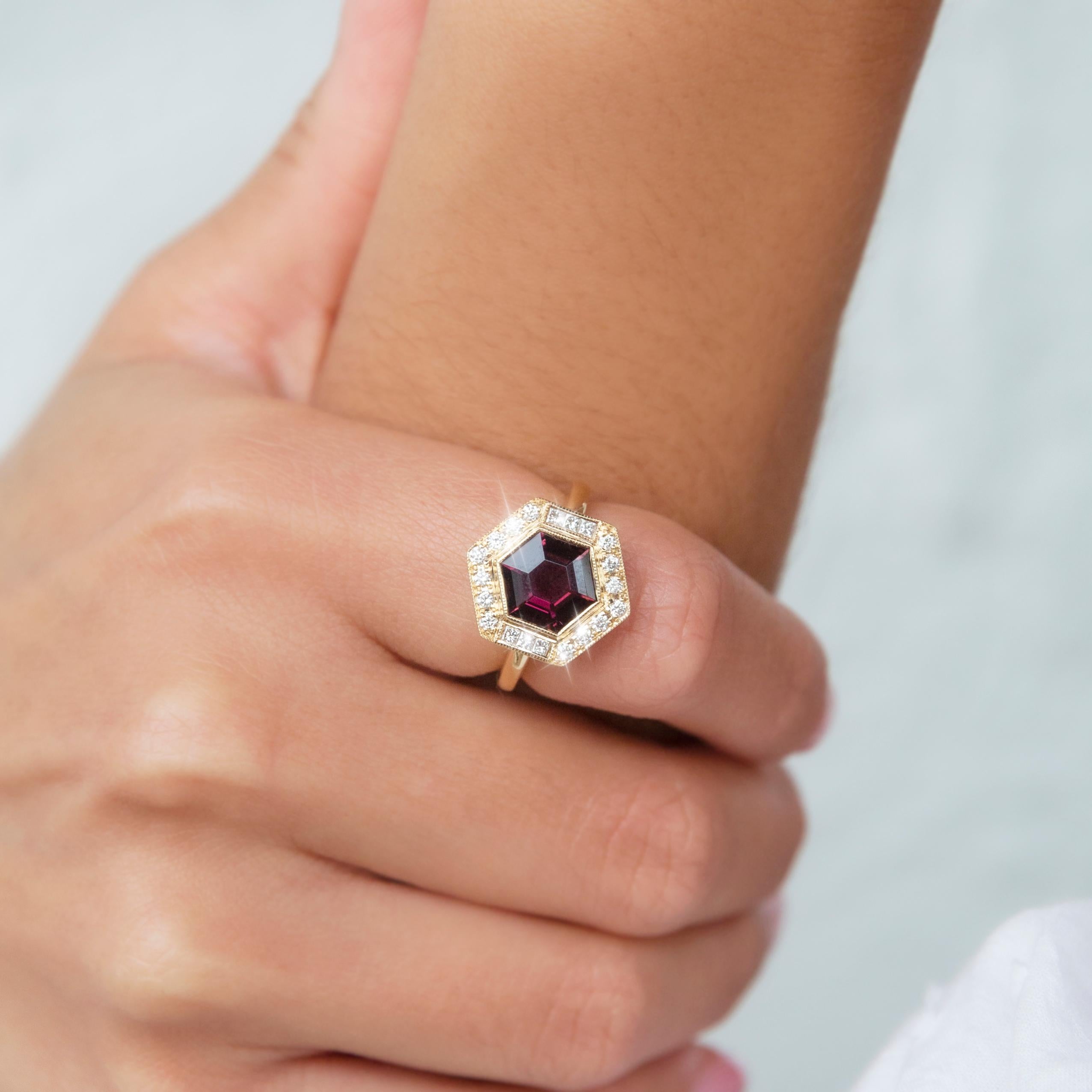 Thoughtfully crafted in 18 carat yellow gold, this wonderful contemporary ring features a darling Reddish-purple hexagonal cut tourmaline at the centre of a graceful basket setting with a glistening border of bead set round brilliant and princess