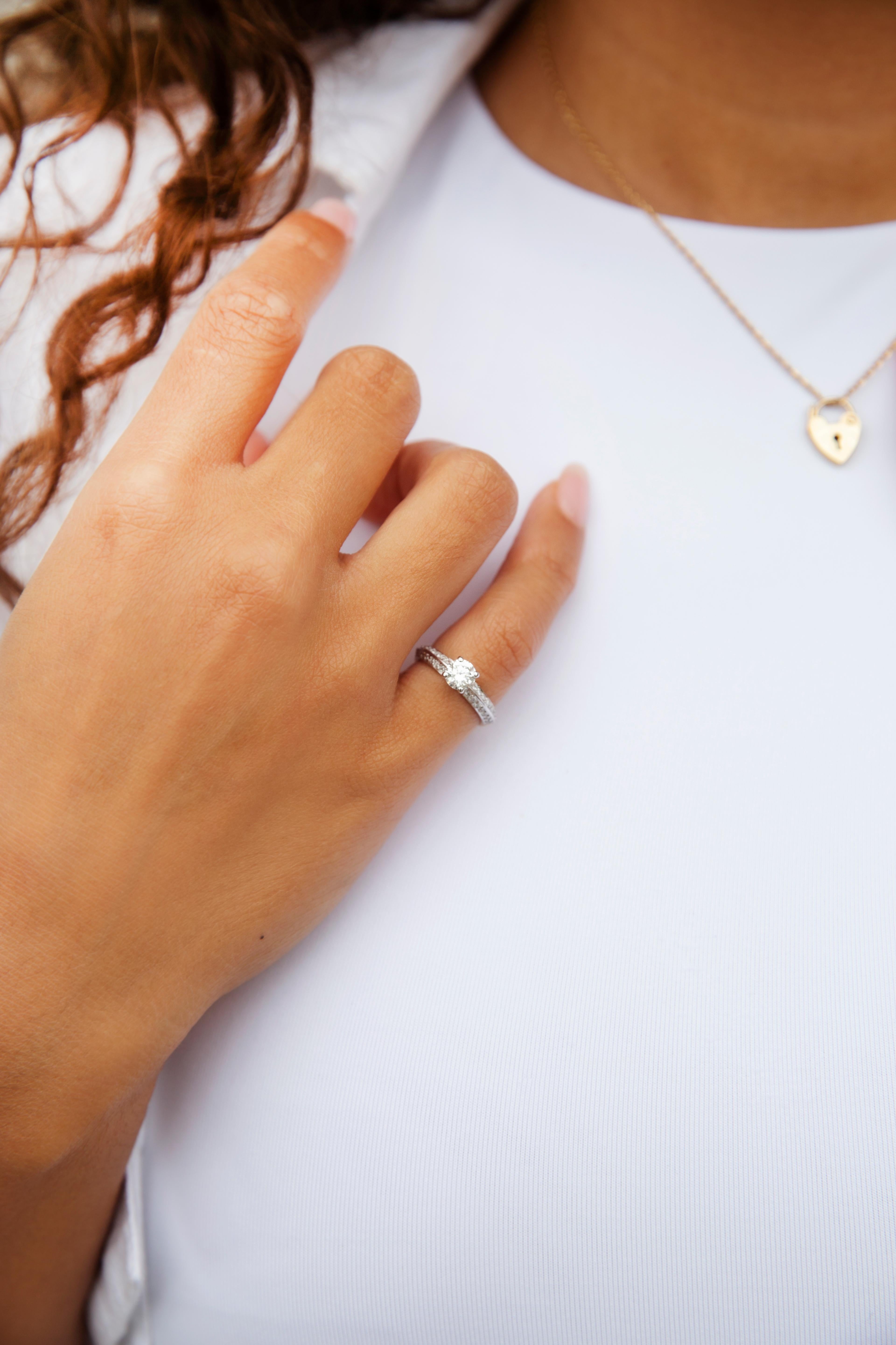 Lovingly crafted in 18 carat yellow and white gold, this gorgeous petite contemporary ring features a gorgeous round brilliant diamond in a claw setting atop knife edge white gold shoulders encrusted with bead set round brilliant cut diamonds. This