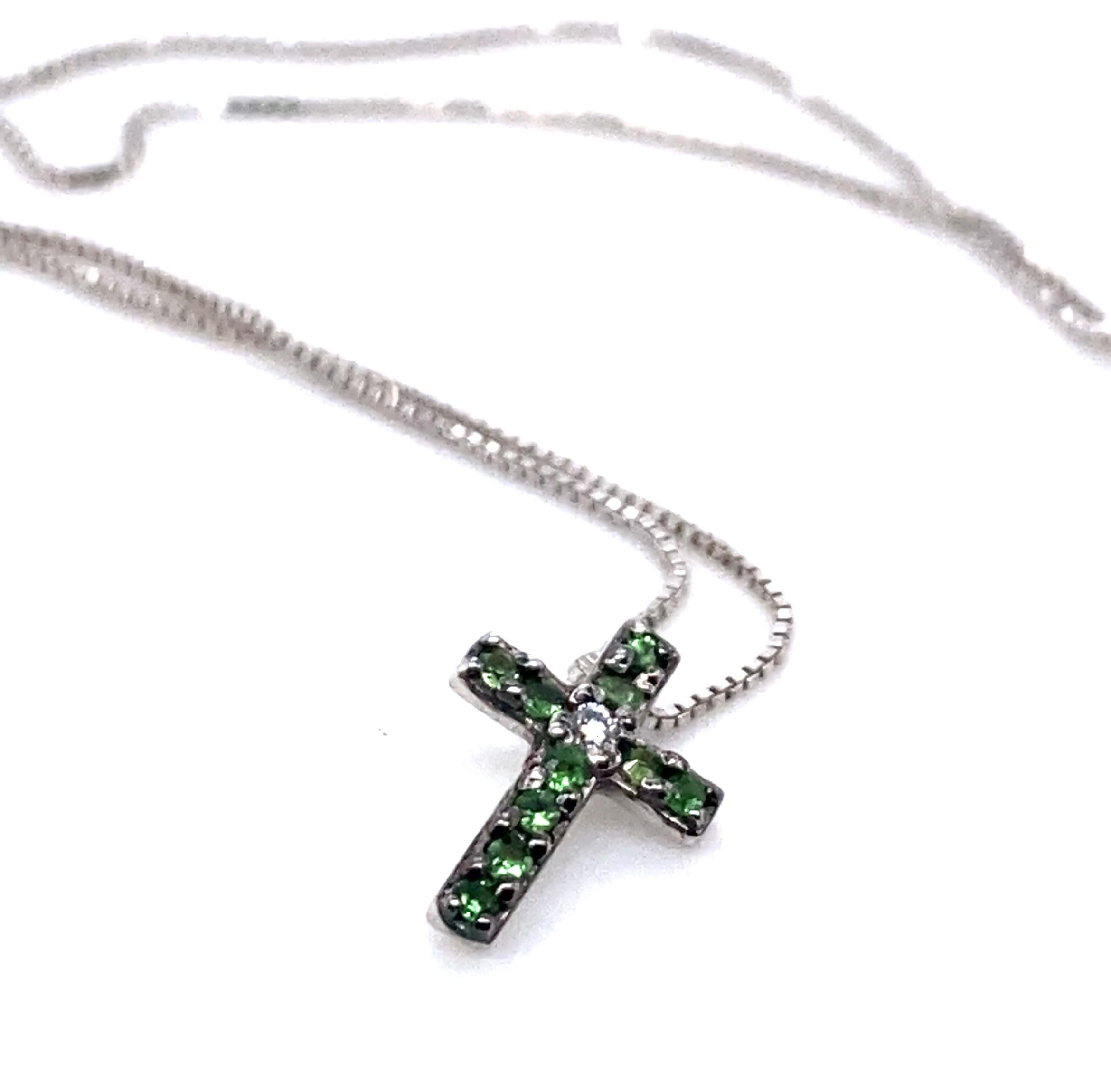 Ein schönes, modernes Kreuz mit einem weißen Diamanten (G VS) und Tsavoriten, gefasst in 18 Karat Weißgold. Die Kette ist aus zartem 18-karätigem Weißgold. Der Anhänger hat einen Durchmesser von 0,6 cm und eine Länge von 0,8 cm. 

Suchen Sie ein