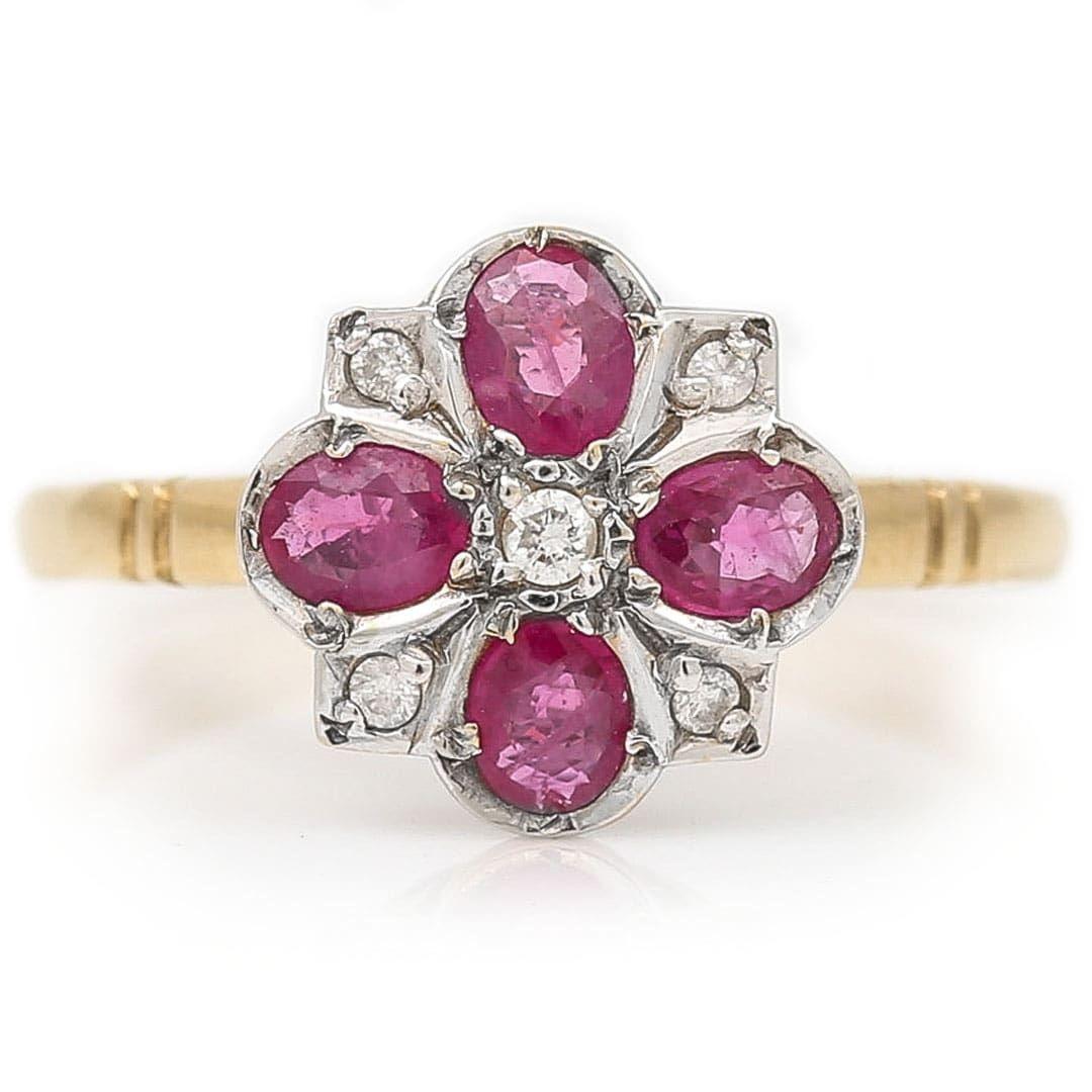 A stylish, geometric designed 18ct gold vintage ruby and diamond floral cluster ring dating from the 1990s. The head of the ring is designed in a floral geometric pattern with 4 oval cut rubies interspersed with 5 brilliant cut diamonds set in