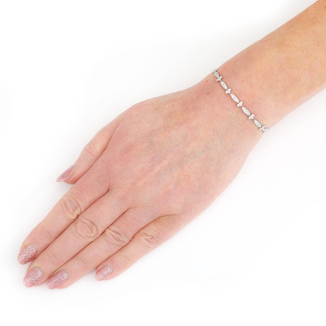 A delicate and pretty 18ct white gold diamond bracelet. This elegant pave-set diamond bracelet has an antique style, each link with fleur-de-lis inspired motifs. Each link set with three millegrain set brilliant cut diamonds. Fitted with a secure