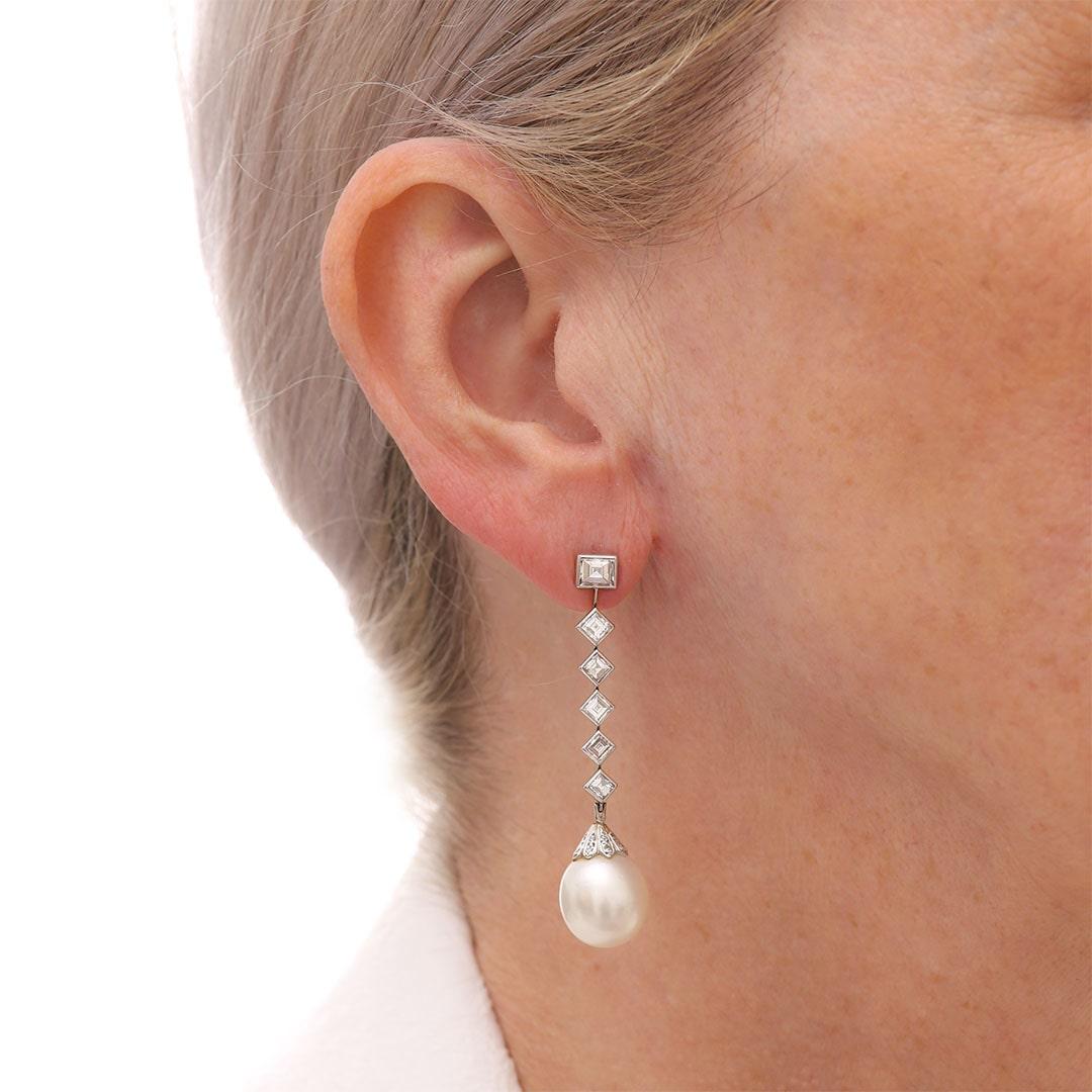 A superb pair of 18ct white gold cultured pearl and baguette cut diamond pendent earrings. Each 11.7mm cultured pearl with a brilliant-cut diamond surmount suspended from articulated links set with step-cut diamonds totalling approx. 3.10ct. The