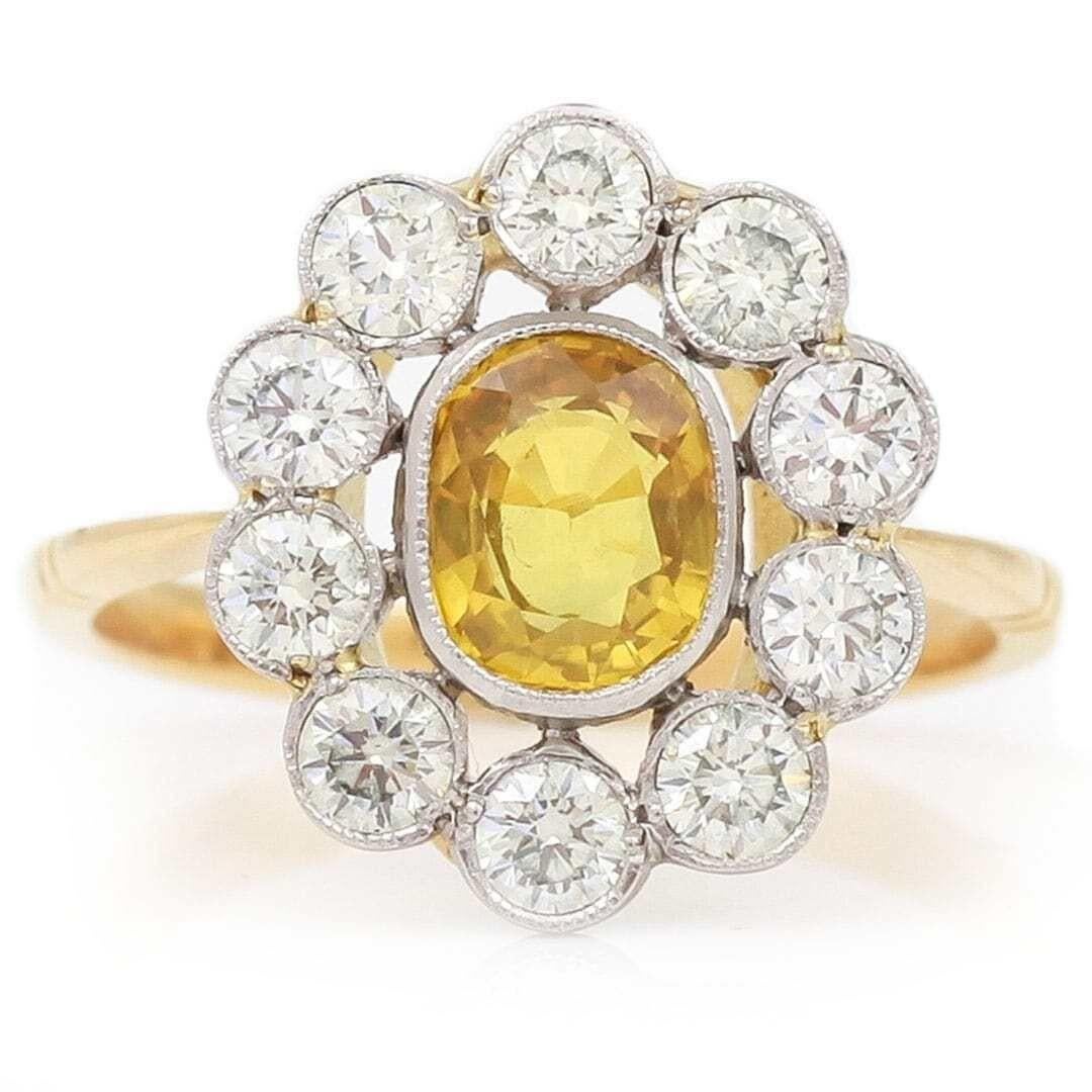 A most attractive 18ct gold yellow sapphire (0.97ct approx.) surrounded by a cluster of bright brilliant cut diamond, estimated at 0.70ct. The yellow sapphire measures 6.9 x 5.7 x 3.3mm with a rich yellow hue radiating energy and a special glow. The