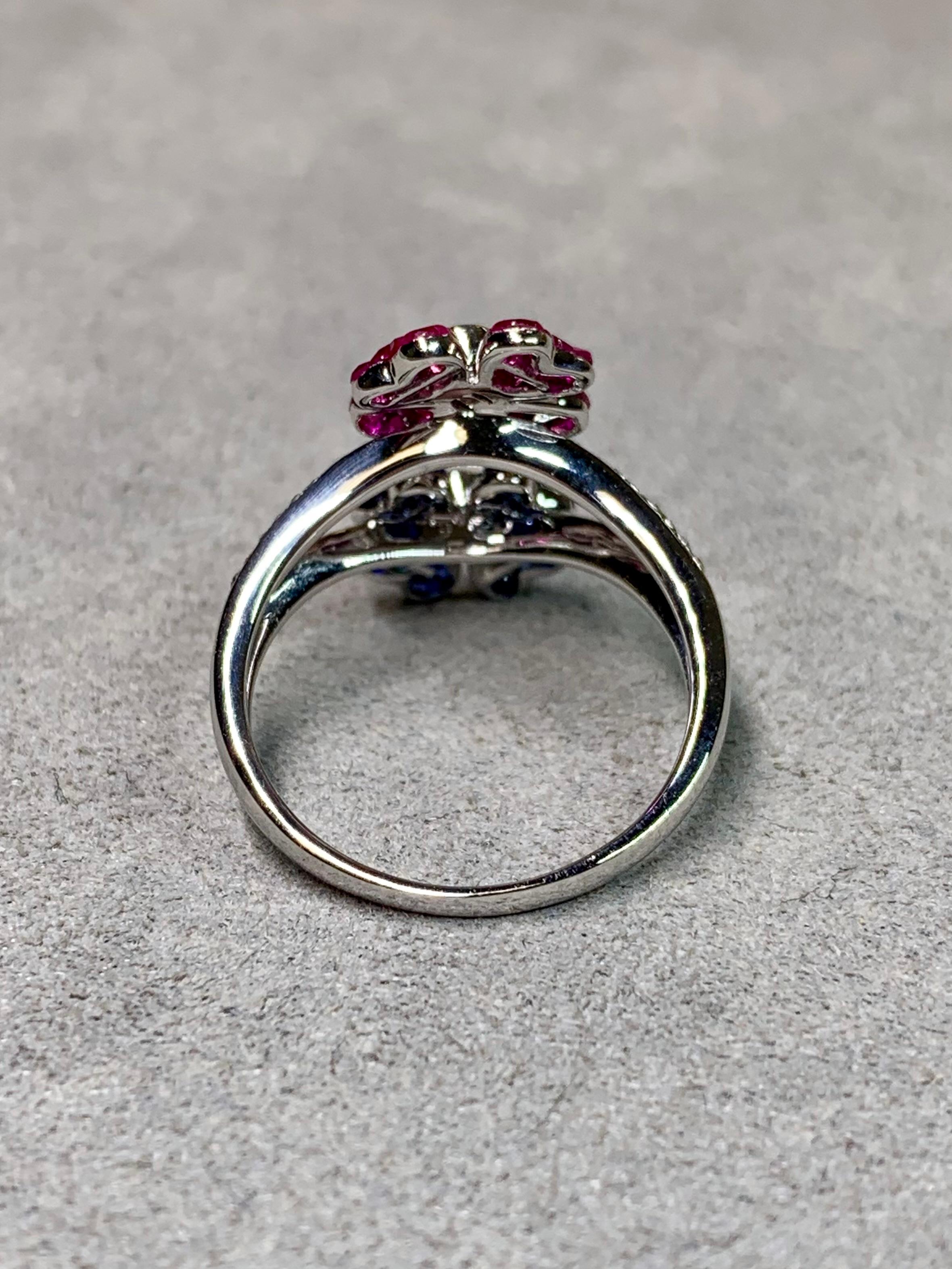 
A contemporary and beautifully crafted ring in 18-karat white gold featuring two striking floral motifs. One flower is composed of precisely calibrated, invisibly set vivid red rubies, while the other is formed from invisibly set royal-blue