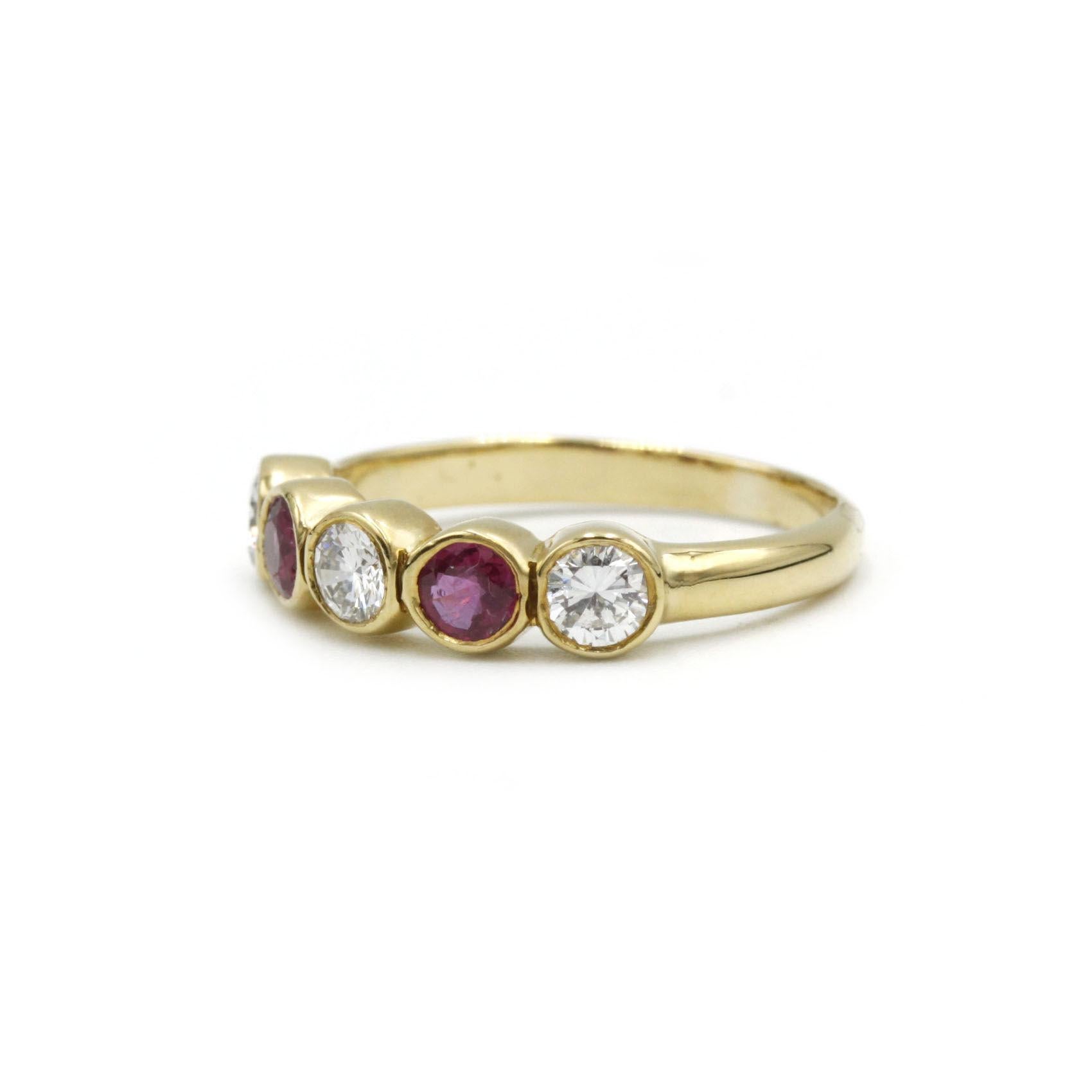 Élégante et discrète, cette bague à demi-bandeau est réalisée en or jaune 18 carats poli et présente une séquence rythmée de trois diamants taille brillant entrecoupés de deux rubis vibrants. Chaque pierre est solidement sertie dans une collerette