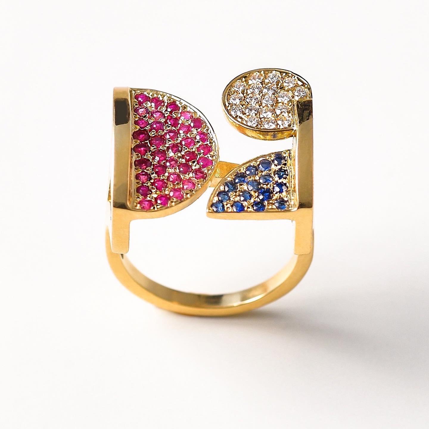 The 'Square’, ring is crafted in 18k gold, hallmarked in Cyprus. This impressive contemporary cocktail ring, comes in a highly polished finish set with  White, VS Diamonds, 0,18 Cts, Rubies 0,45 cts and  Blue Sapphires 0,20 Cts. The 'Square’ ring is