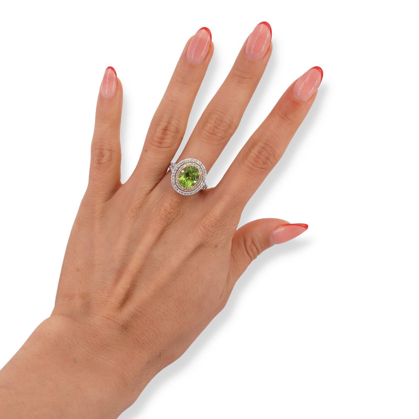 Voici une superbe bague bicolore en 18kt qui met magnifiquement en valeur un péridot ovale central pesant environ 3,25 carats. Cette pierre précieuse exquise rayonne d'une teinte verte vibrante, symbolisant le renouveau et la prospérité. La bague