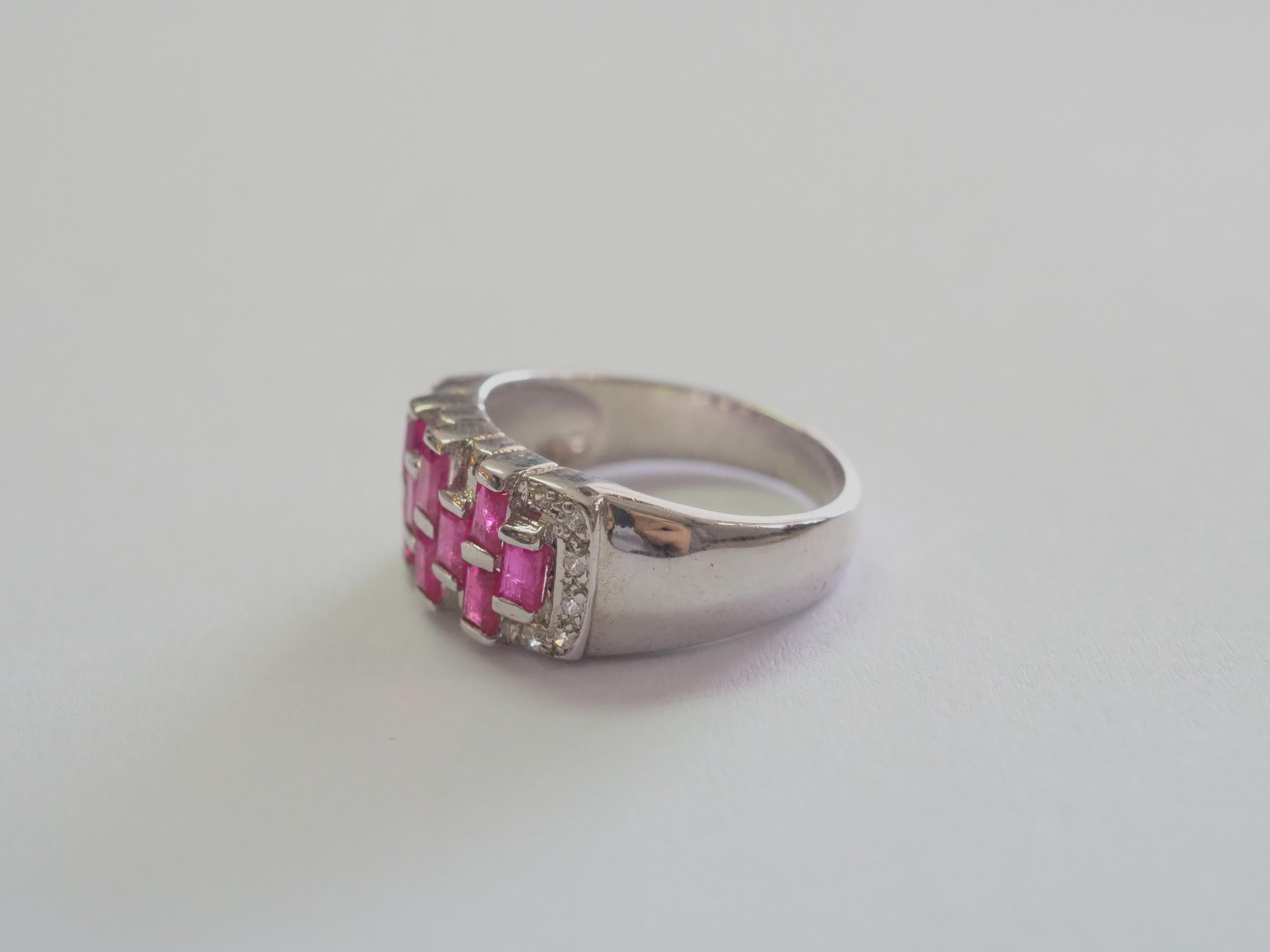 Dieser Ring ist ein schöner Bandring aus massivem Sterlingsilber. Der Ring ist mit einem natürlichen, rosaroten Baguette-Rubin verziert, der auf der Vorderseite des Rings wunderschön gefasst ist. Die weißen Steine sind Cubic Zirconia. Der Rubin ist