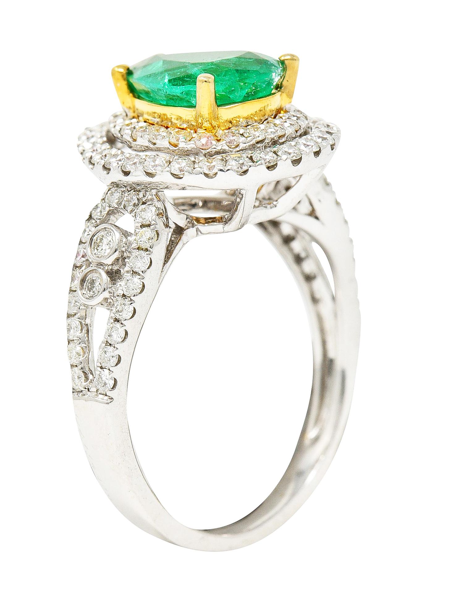 Cluster ring centers a pear cut emerald weighing approximately 1.50 carats. Bluish green in color and semi-transparent with natural inclusions. Set in yellow gold and surrounded by a double diamond halo. And flanked by stylized split shoulders