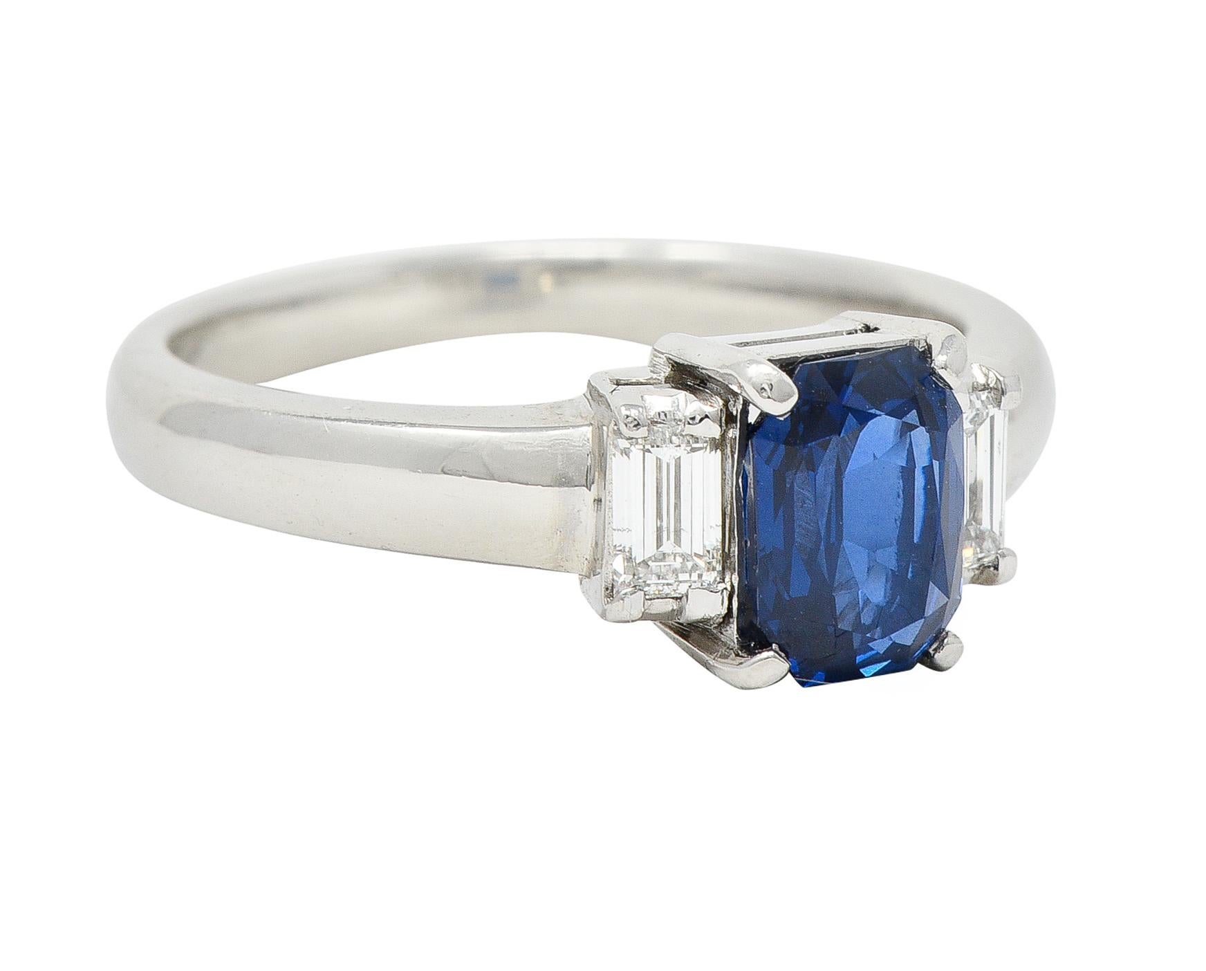 Centering a cushion cut sapphire weighing 1.78 carats total - transparent medium blue. Flanked by baguette cut diamonds - all prong set in baskets. Weighing 0.23 carat total - G/H color with VS clarity. With high polish finish. Inscribed with carat