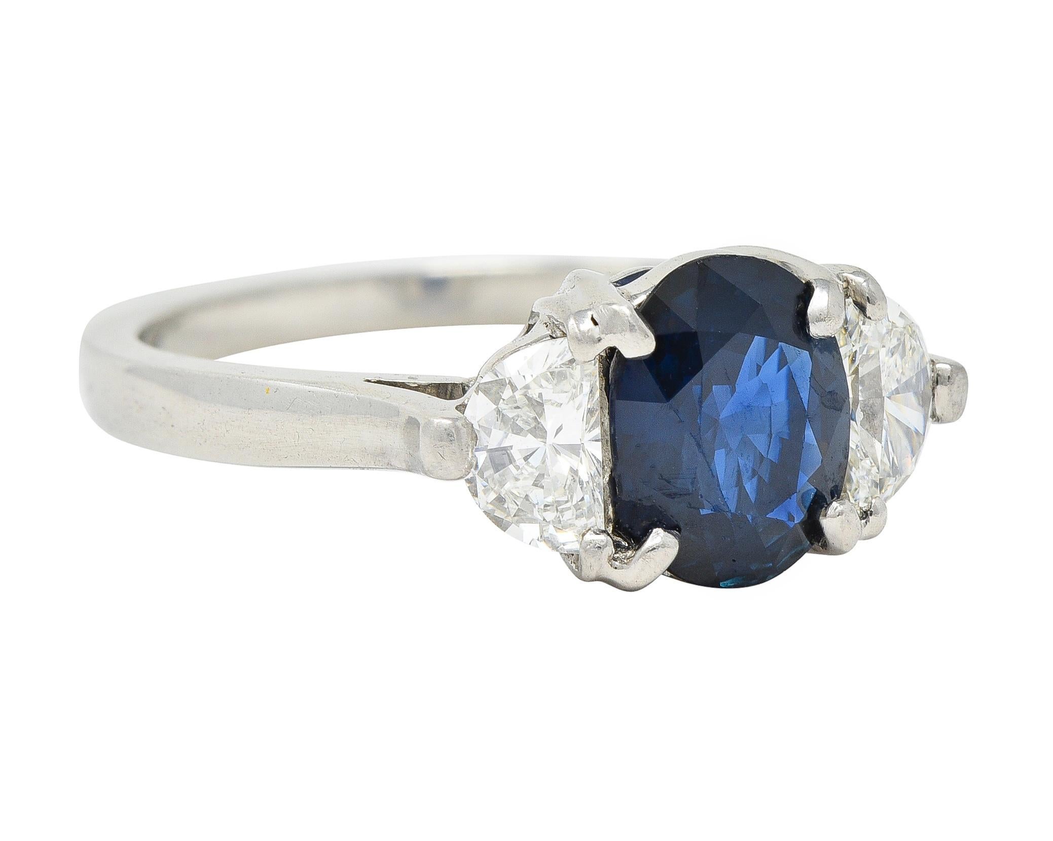 Centering and oval cut sapphire weighing approximately 1.59 carats - transparent dark blue 
Prong set in basket and flanked by half-moon cut diamonds 
Weighing approximately 0.48 carat total - J color with VS2 clarity
Prong set in cathedral