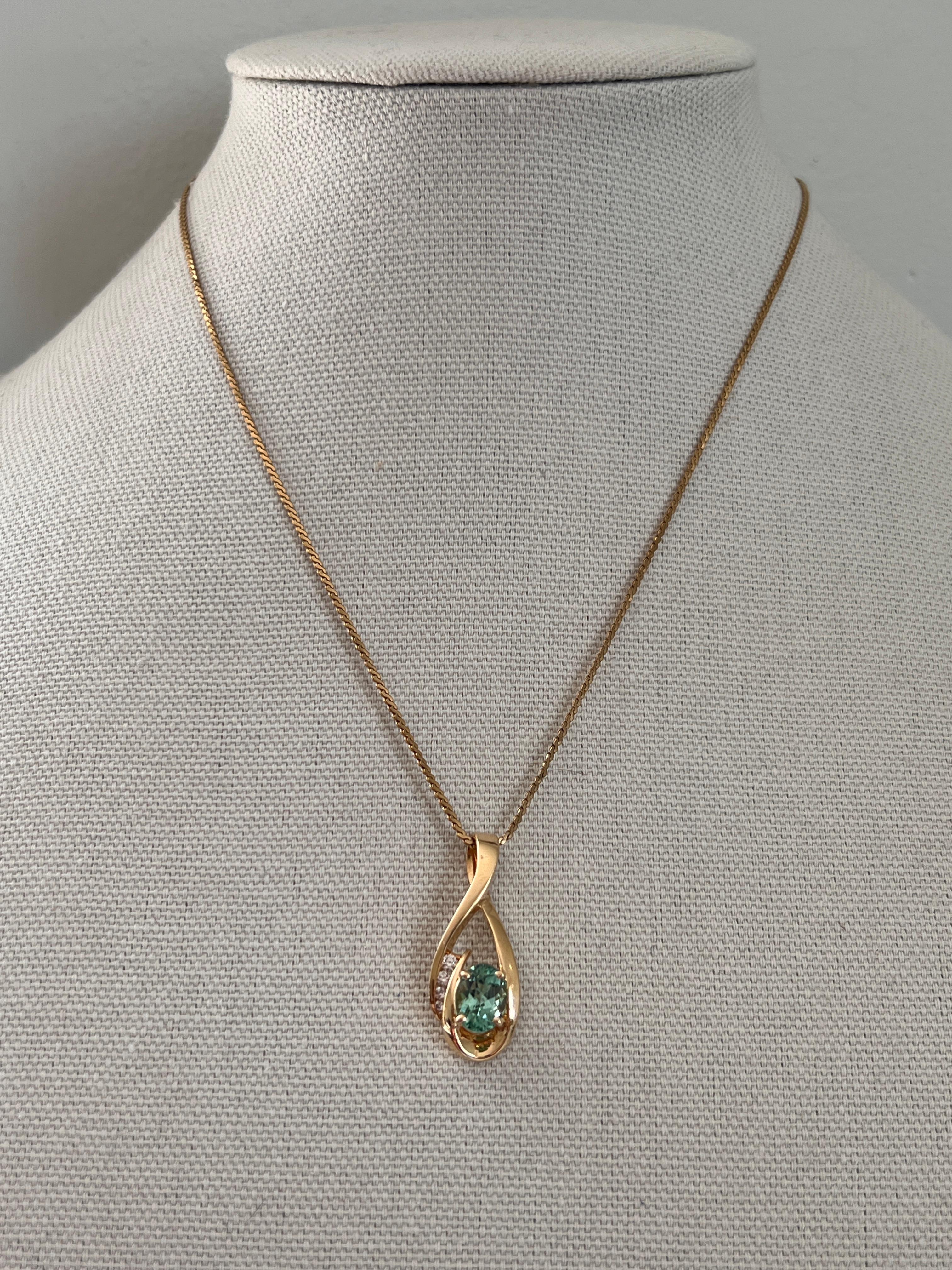 Un pendentif contemporain en or jaune 14 carats orné d'une tourmaline vert menthe ovale mesurant environ 9,2 x 7,35 mm et pesant environ 2,33 carats. Accentué par quatre diamants ronds de taille brillant totalisant environ 0,132 carat, de couleur
