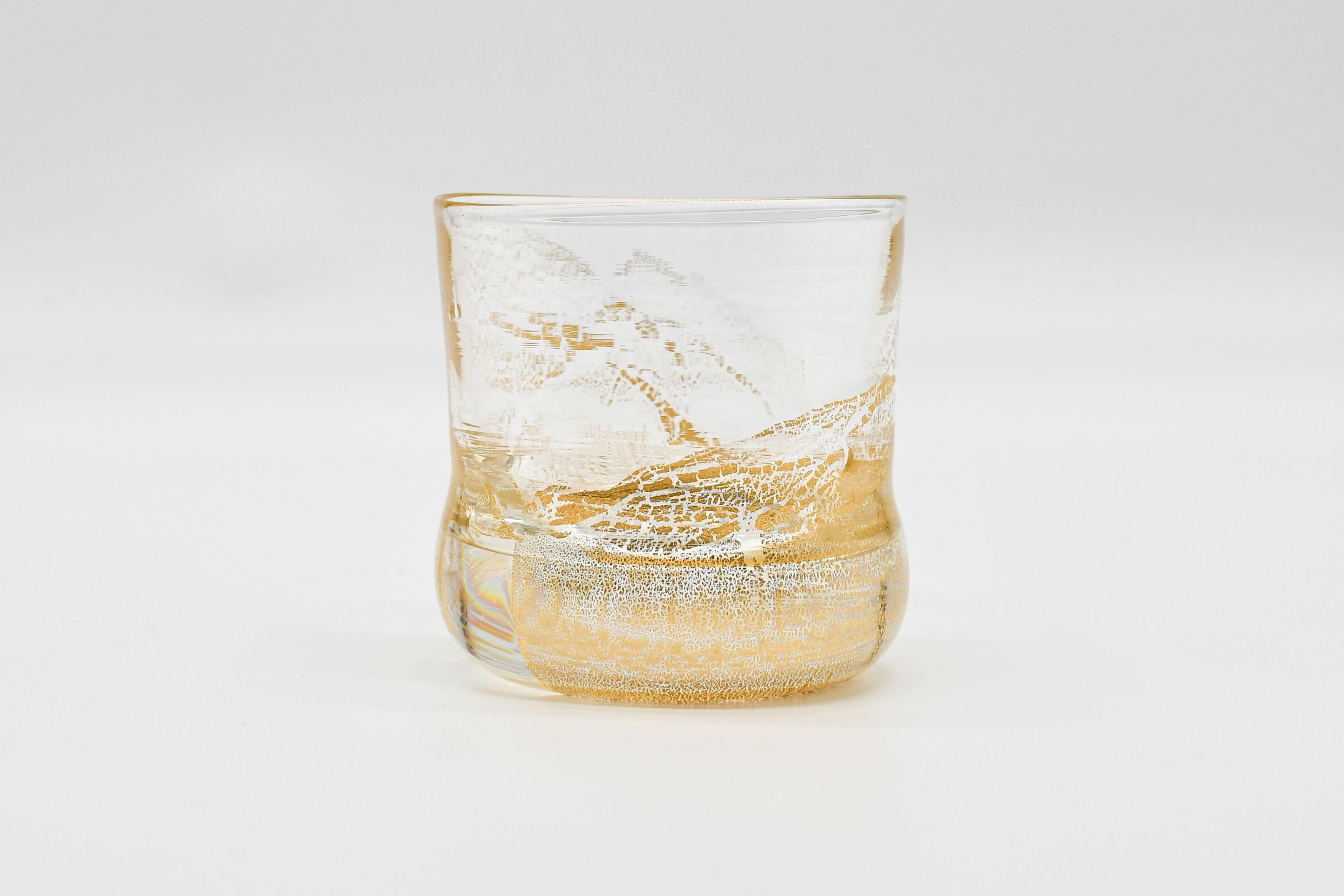 24K is a sophisticated whiskey set handcrafted from clear mouth-blown glass and adorned with pure 24 K gold leaves, showcasing exceptional craftsmanship. In addition to the unique tumblers, this set also includes a matching whiskey bottle and cigar