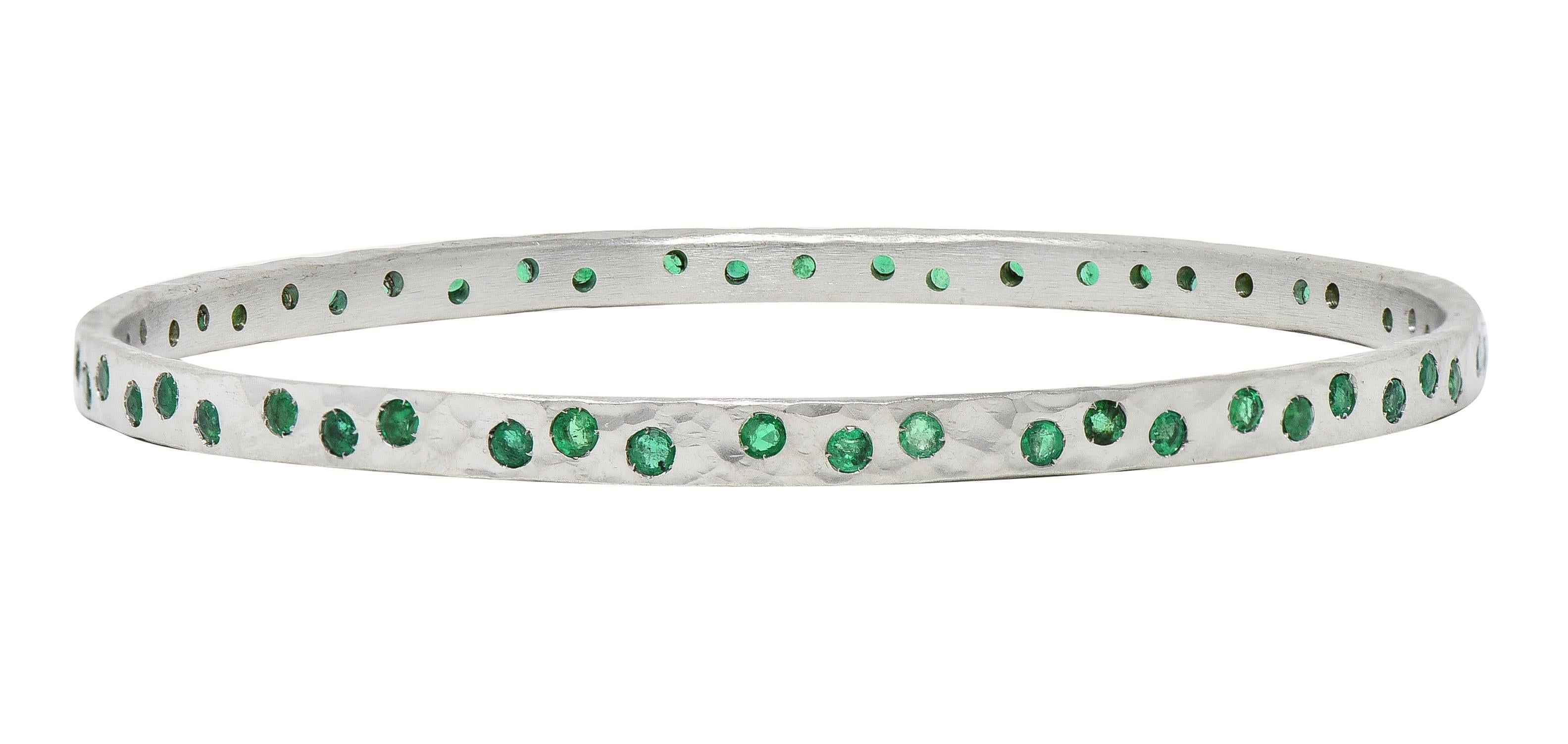 Designed as a white gold bangle with hammered texture throughout 
Featuring round cut emeralds flush set fully around 
Weighing approximately 2.70 carats total 
Transparent light to medium green 
Stamped for 14 karat gold
With maker's mark
Circa: