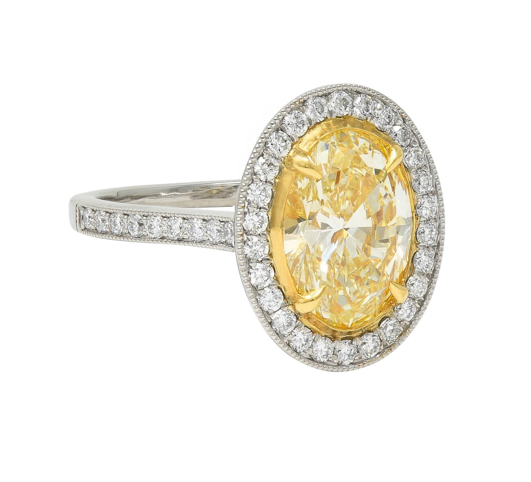 Centering an oval cut diamond weighing 2.16 carats - yellow (Y/Z) color with VS1 clarity
Prong set in gold with a platinum halo surround bead set with round brilliant cut diamonds
With additional diamonds bead set in cathedral shoulders and pierced