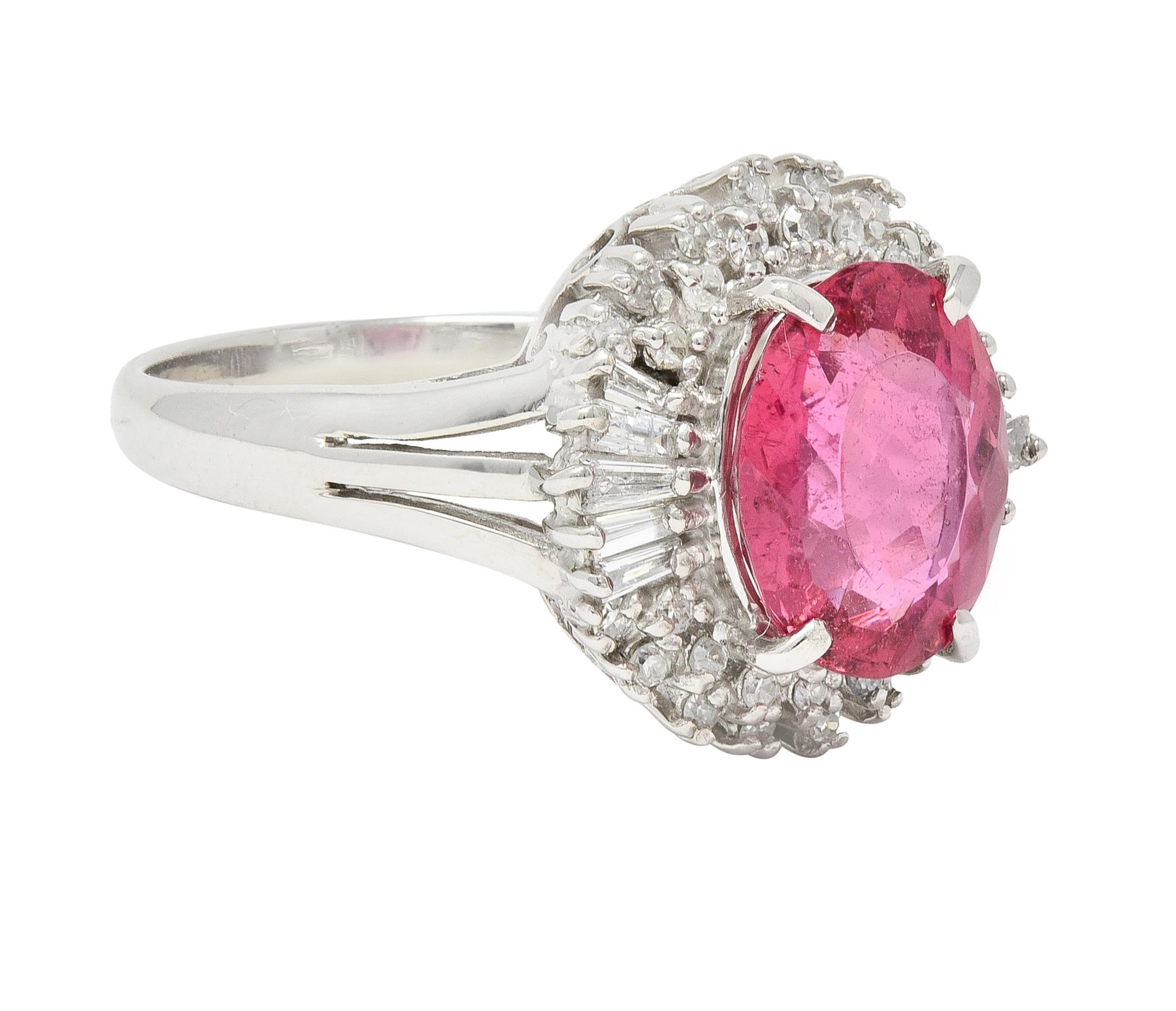 Centering an oval cut spinel weighing 2.50 carats - transparent medium orangy pink in color 
Prong set with a recessed halo surround comprised of single and baguette cut diamonds 
Weighing approximately 0.35 carat total - eye clean and