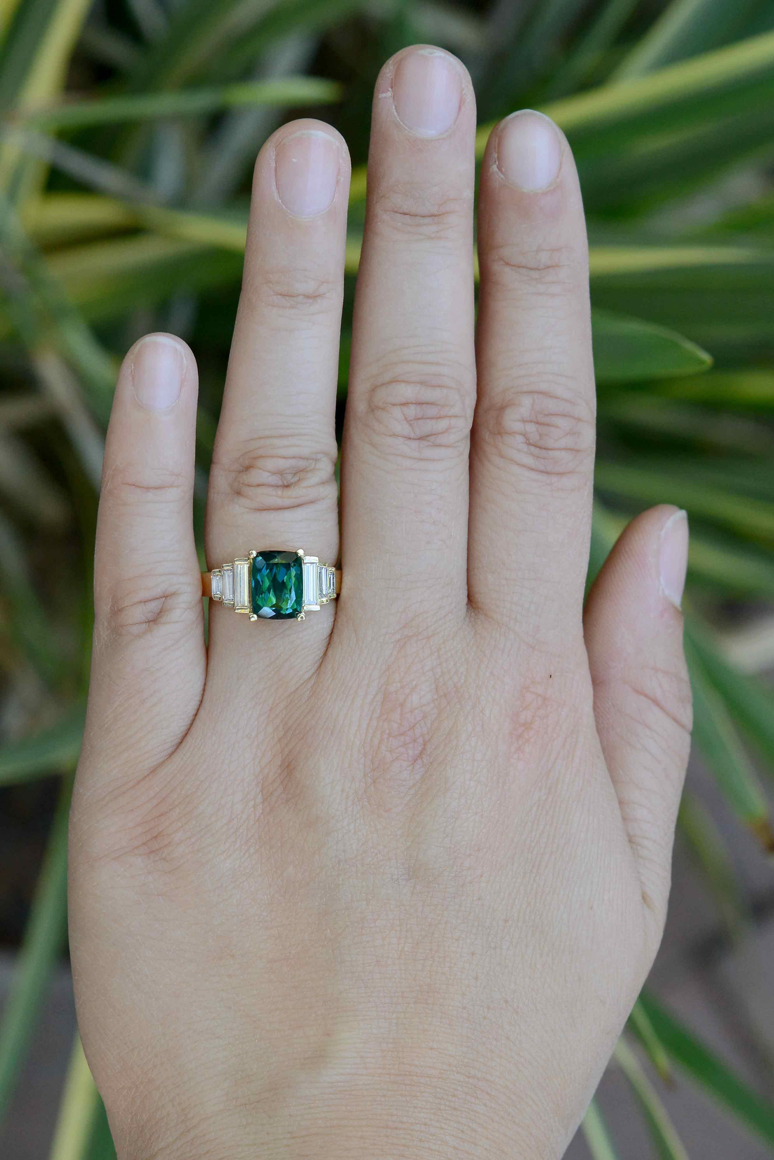 A remarkable tourmaline and diamond engagement ring. The indicolite exhibited in the center displays an incredible blue-green color that is exclusively found in this rare form of tourmaline. Tapered with a staircase of striking baguette diamonds all