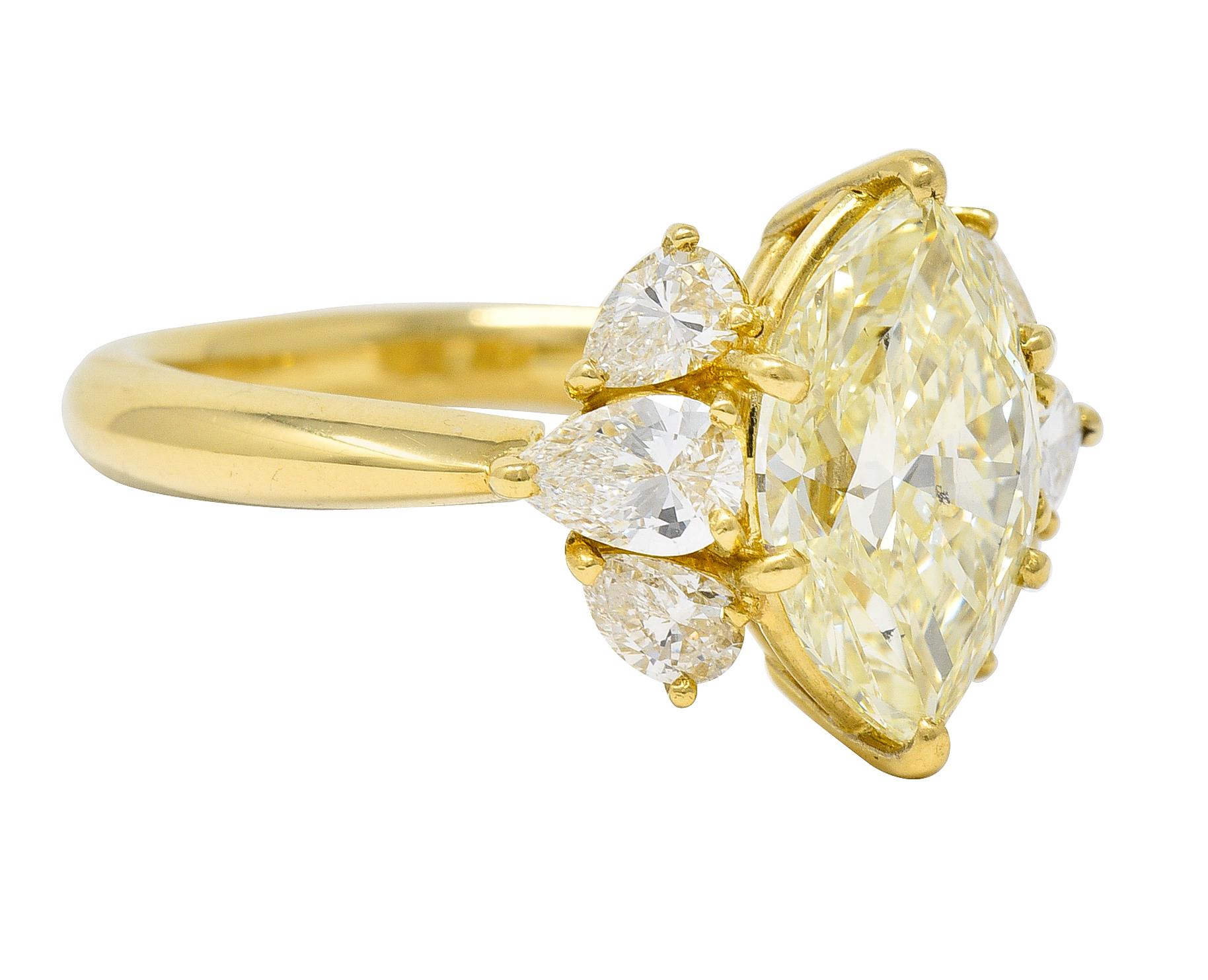 Centering a marquise cut diamond weighing 2.18 carats - Fancy Light Yellow in color with SI1 clarity. Prong set in basket and flanked by clusters of pear cut diamonds. Weighing 0.82 carat total - G/H color with VS clarity. Prong set in baskets and