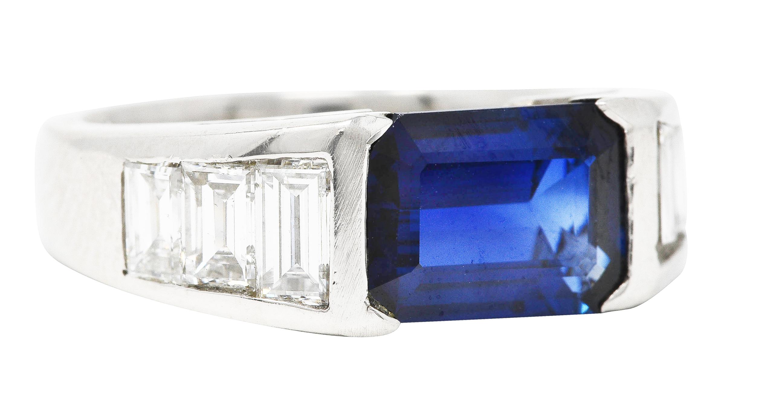 Wide band ring features an emerald cut sapphire weighing 2.18 carats. Eye clean and royal blue in color - uniform and medium dark in saturation. Half bezel set East to West into cathedral shoulders. Flanked by channel set baguette cut diamonds -