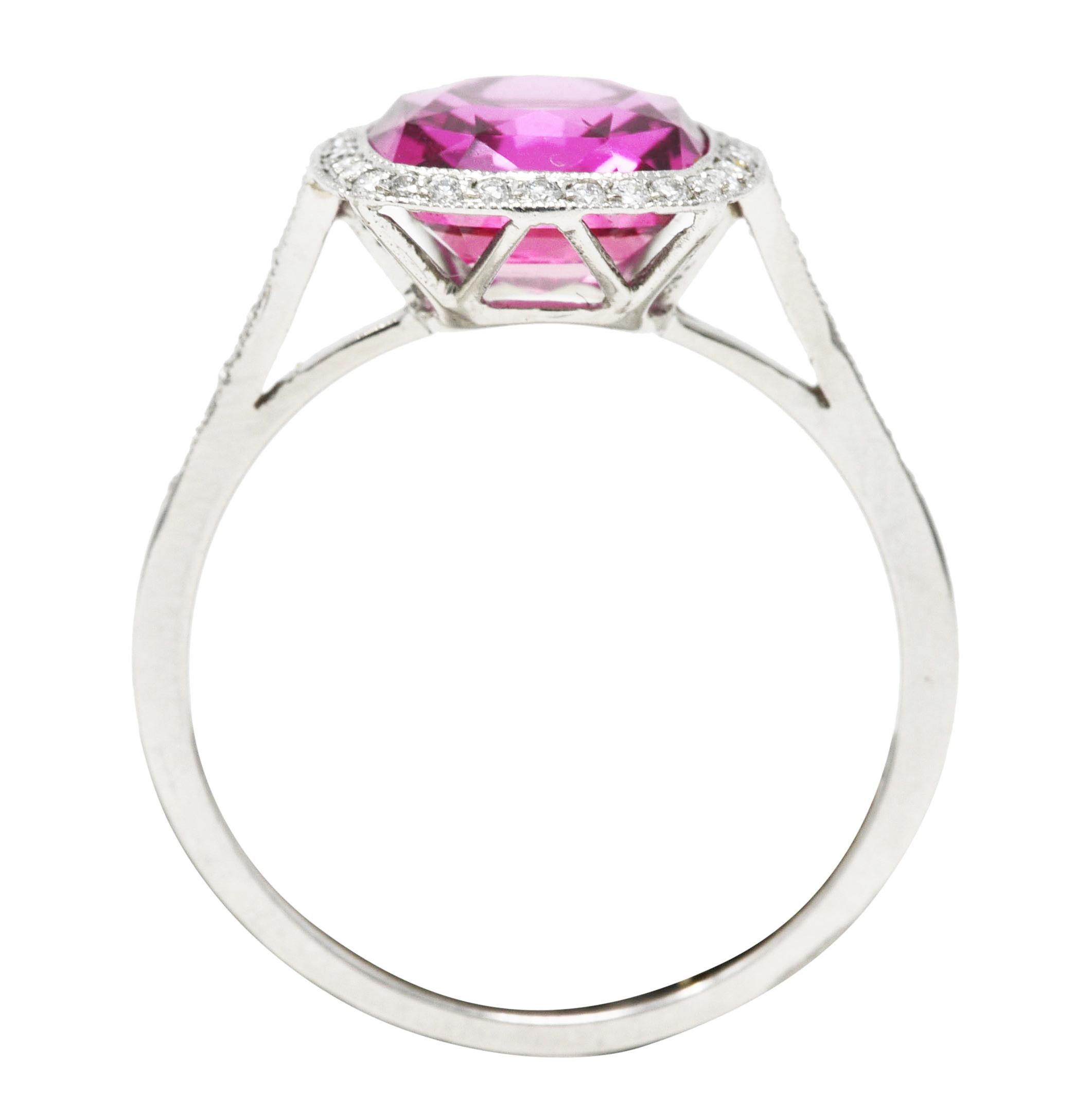 Featuring a mixed cushion cut Madagascar pink sapphire weighing approximately 3.30 carats. Transparent and saturated pink in color - medium dark in tone. Surrounded by a round brilliant cut diamond halo and diamond accented cathedral shoulders.
