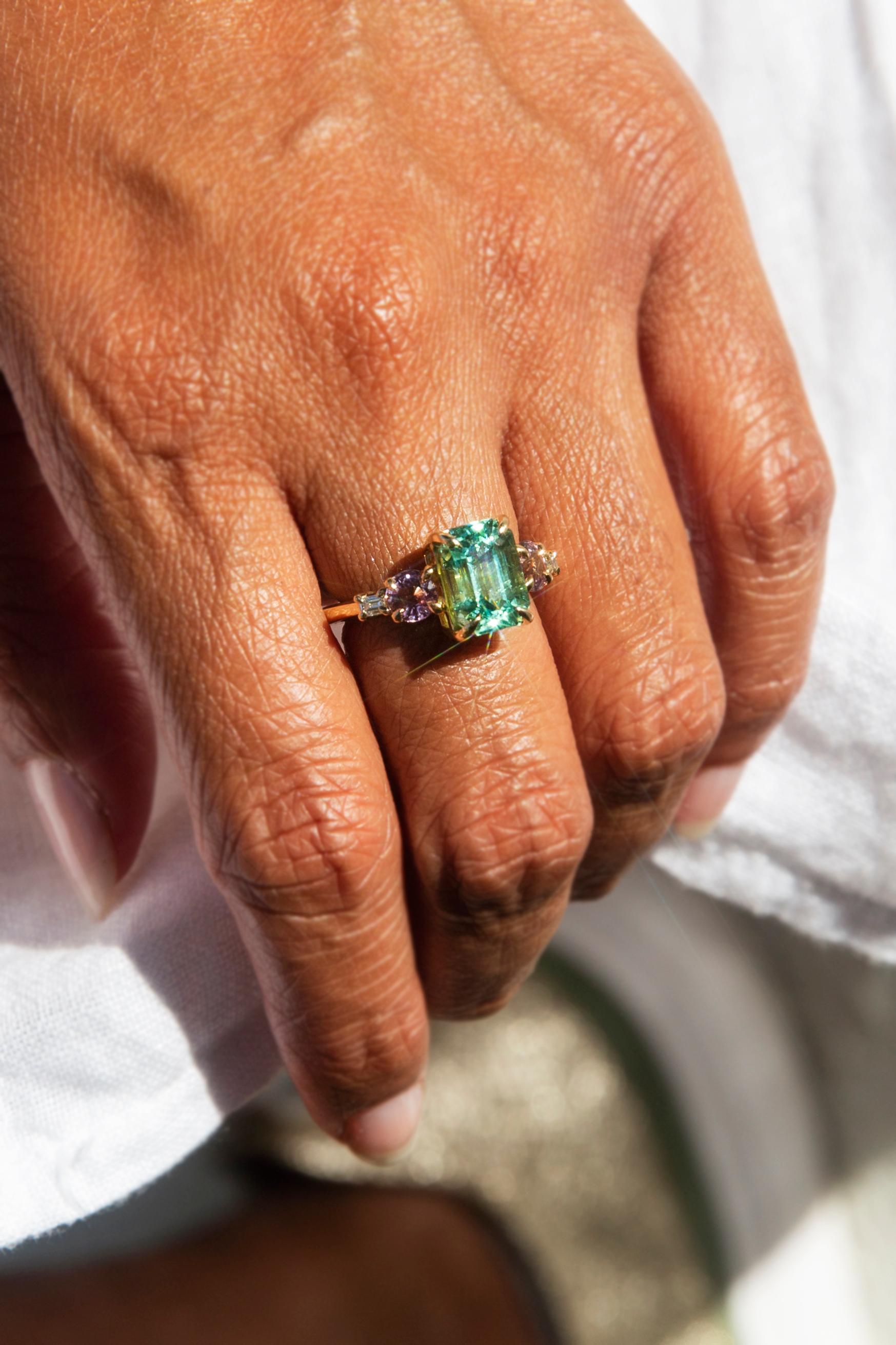 Forged in 18 carat yellow gold, this contemporary wonder features a gorgeous 3.80-carat emerald cut mint green tourmaline flanked by two alluring round pink spinels and two scintillating round brilliant cut diamonds. We have named this fabulous