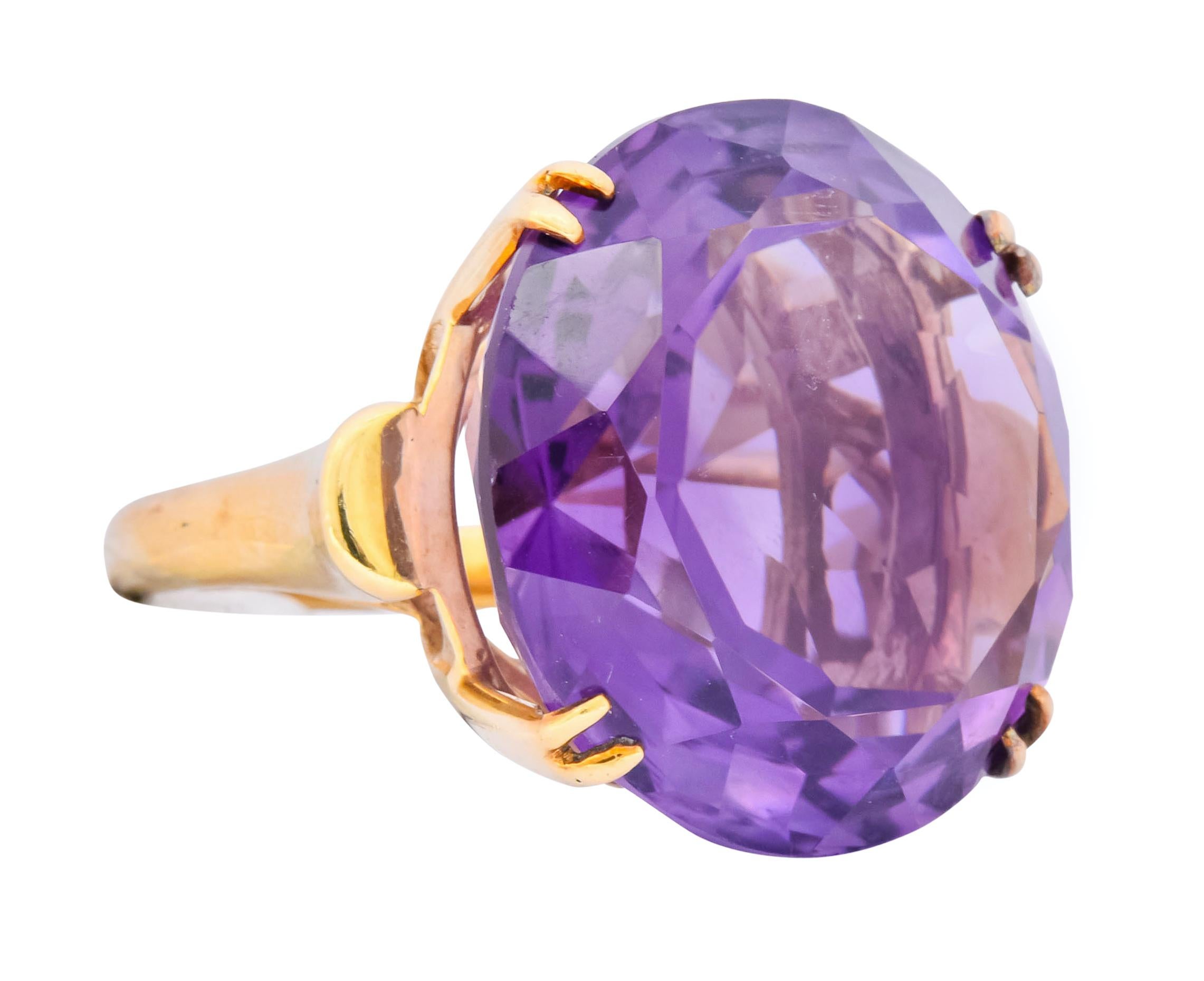 Centering a large, round, mixed cut amethyst weighing approximately 40.82 carats total, transparent and a medium-light reddish-violet

Basket set with split prongs and flanked by a highly polished half moon motif at each shoulder

With maker's mark