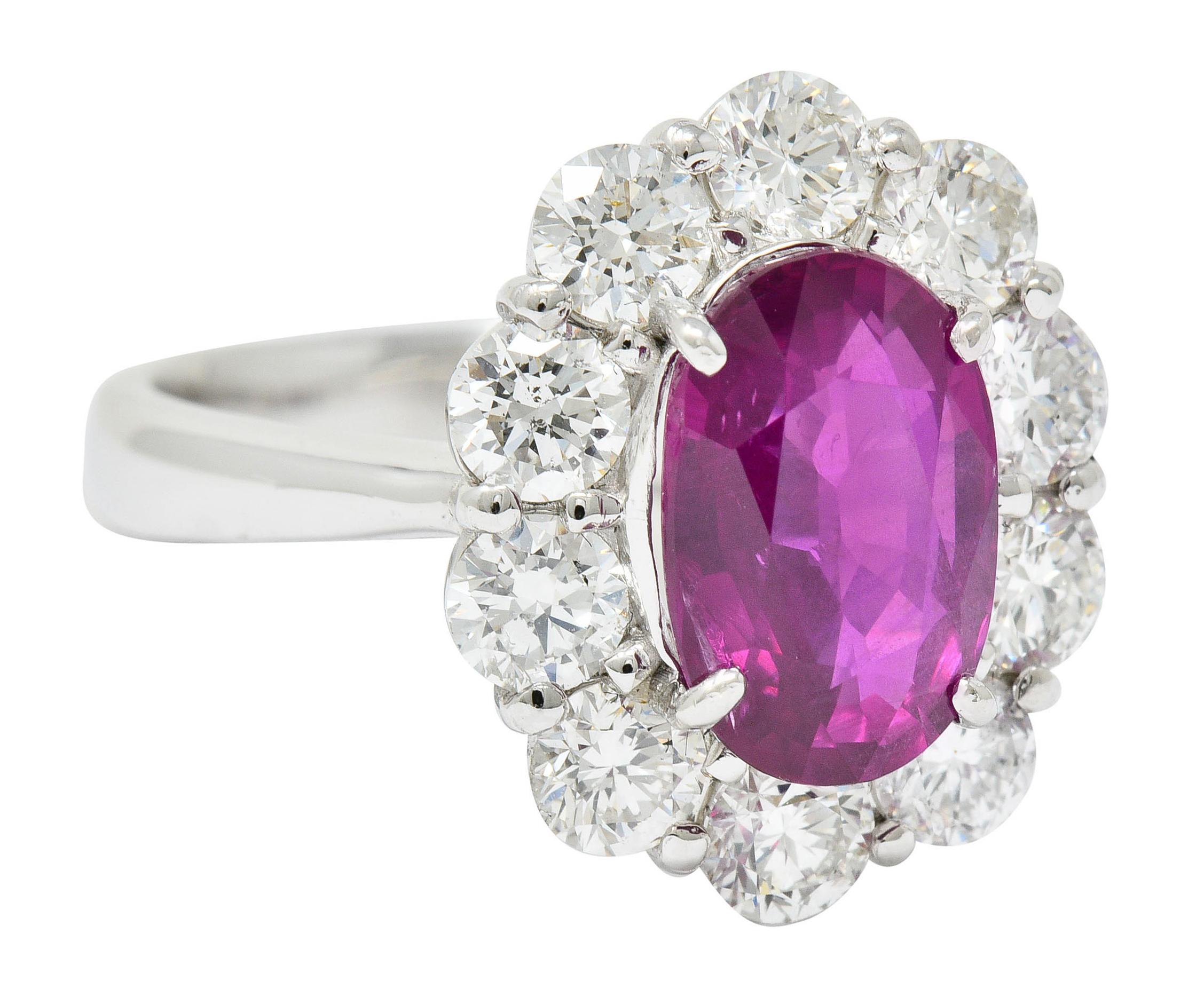 Cluster style ring centering an oval cut ruby weighing 3.03 carats; translucent purplish-red color

No indications of heat with slight and romantic chatoyancy; Mozambique origin

Surrounded by round brilliant cut diamonds weighing 1.63 carats; G/H