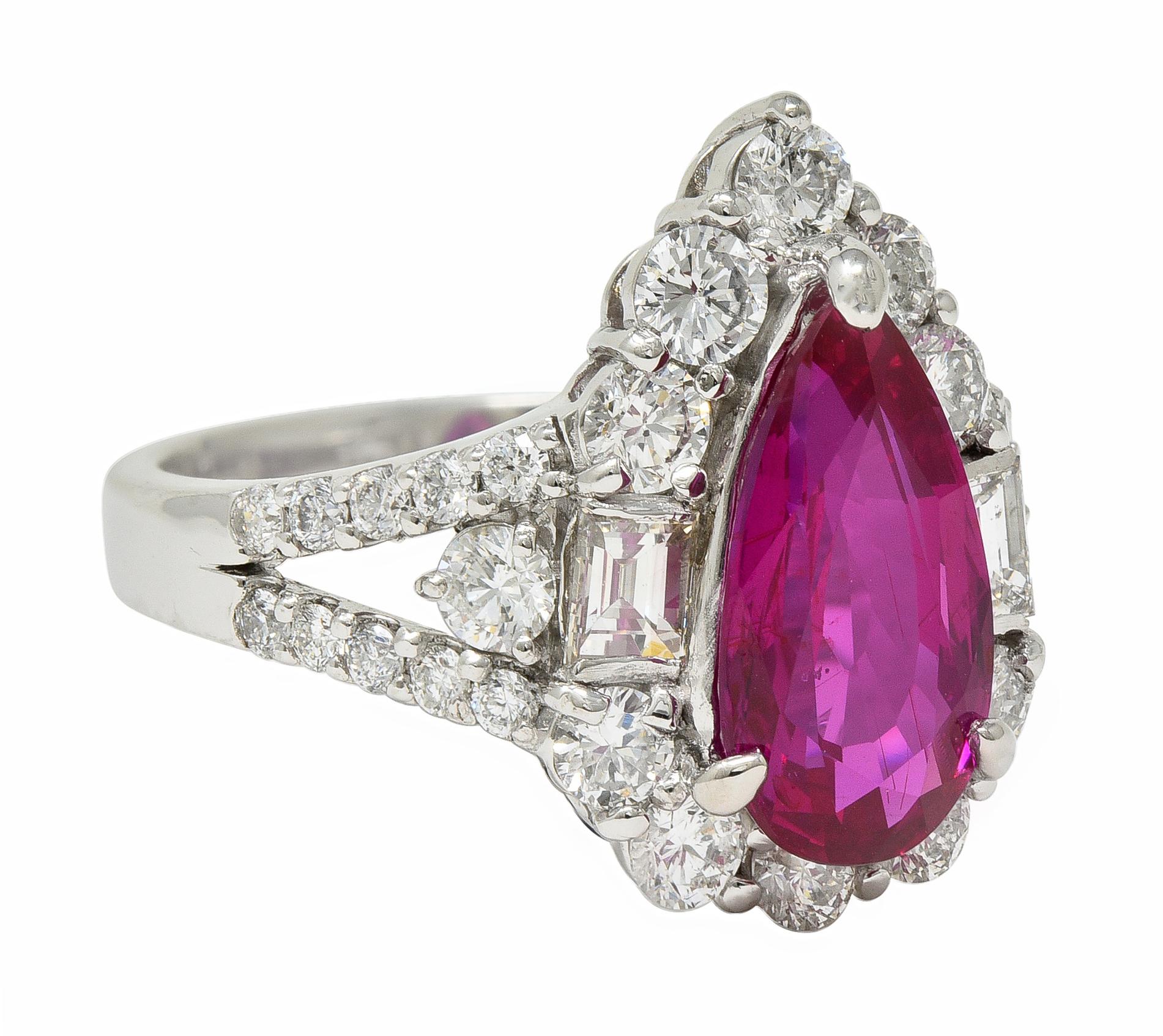 Centering a pear cut ruby weighing 3.34 carats - transparent pinkish red in color
Natural Mozambique in origin with no indications of heat treatment 
Prong set with a halo surround of round brilliant and baguette cut diamonds
Flanked by split
