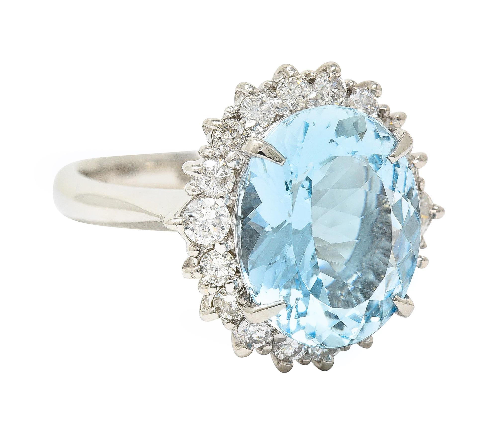 Centering an oval cut aquamarine weighing 4.87 carats total 
Transparent light blue in color - prong set
With a halo surround of round brilliant cut diamonds 
Weighing 0.68 carat total - G/H color with VS clarity
Pring set in a wire basket
With high