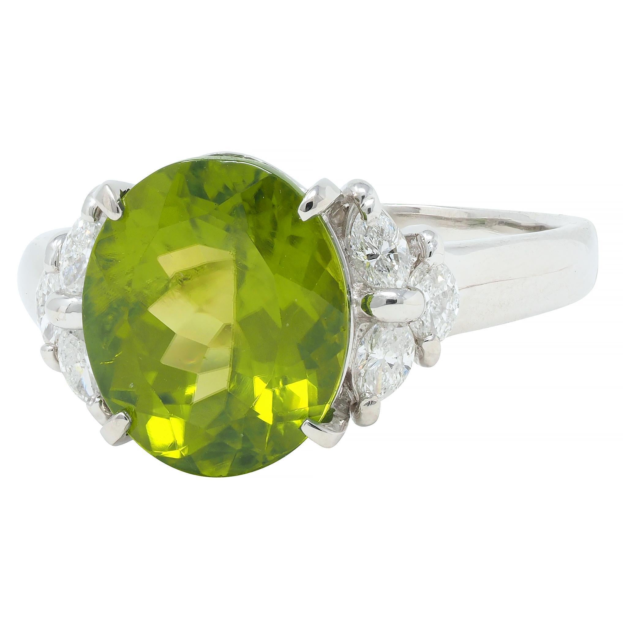 Centering an oval mixed-cut peridot weighing approximately 5.46 carats - transparent medium yellow green
Prong set in a pierced basket and flanked by cathedral shoulders
Prong set with clustered marquise cut diamonds
Weighing approximately 0.45