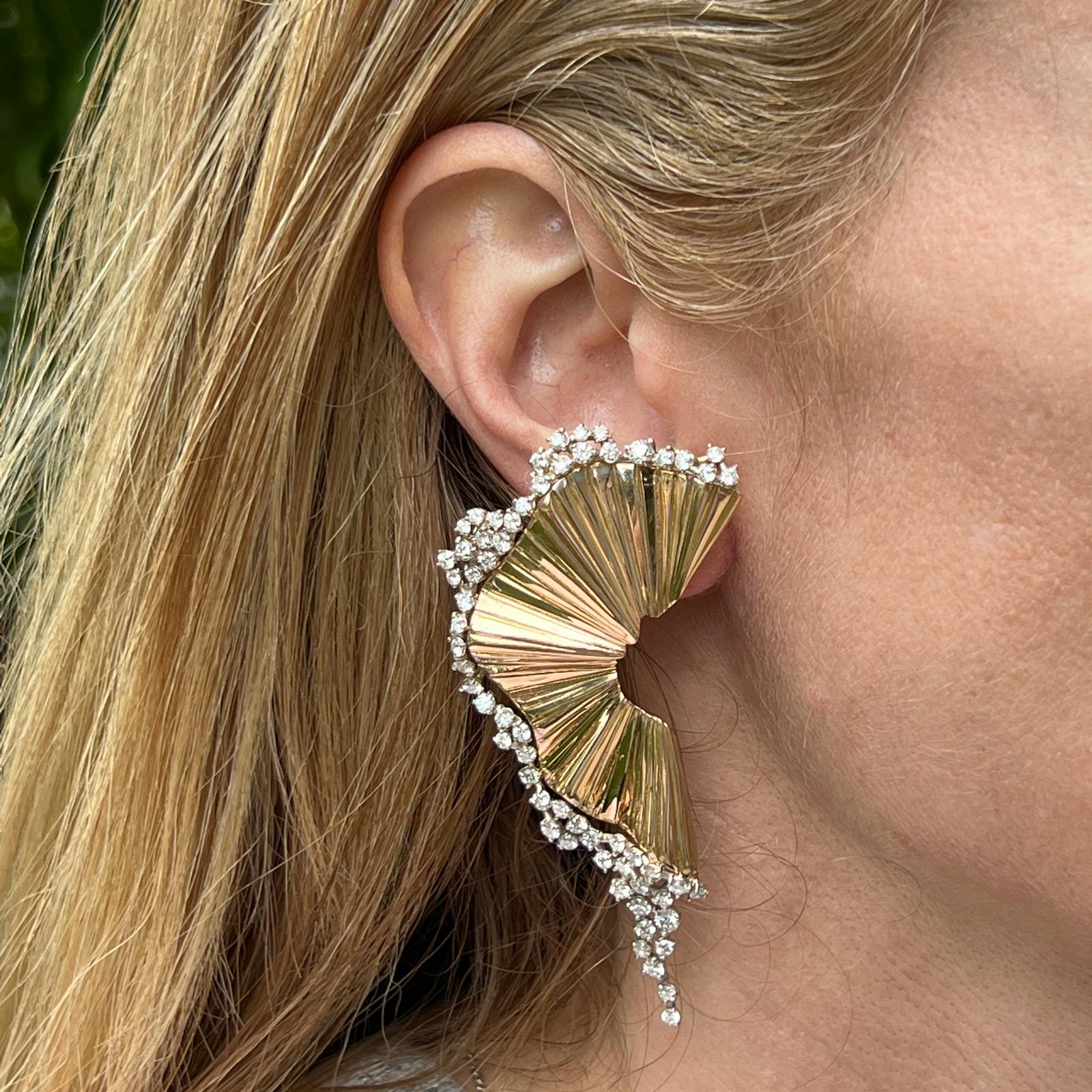 Diamond fan statement earrings handcrafted in 18 karat yellow gold. The earrings feature 120 round brilliant cut diamonds weighing approximately 6.00 CTW and graded H-I color and VS clarity. The earrings measure 1.25 x 3.00 inches, leverback clip