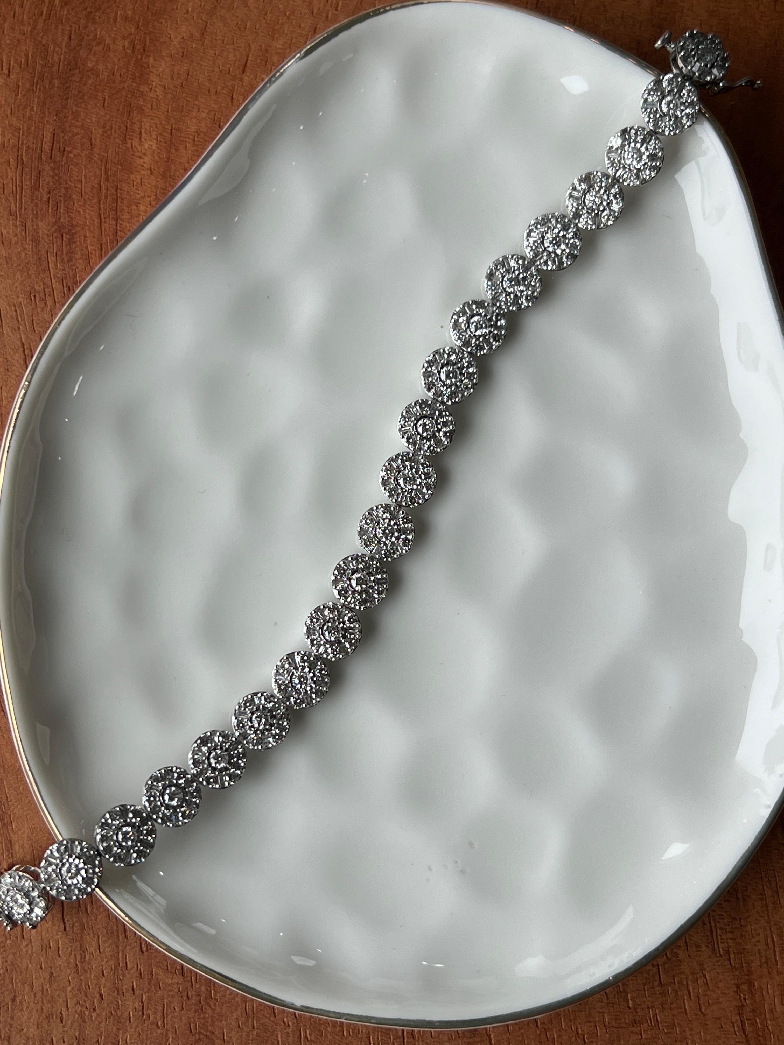 Questo braccialetto contemporaneo in oro bianco 10 carati si fa notare per l'accattivante design circolare e per il notevole scintillio. Realizzato con un mix di 147 diamanti tondi taglio brillante per un totale di circa 5,06 carati e 126 diamanti
