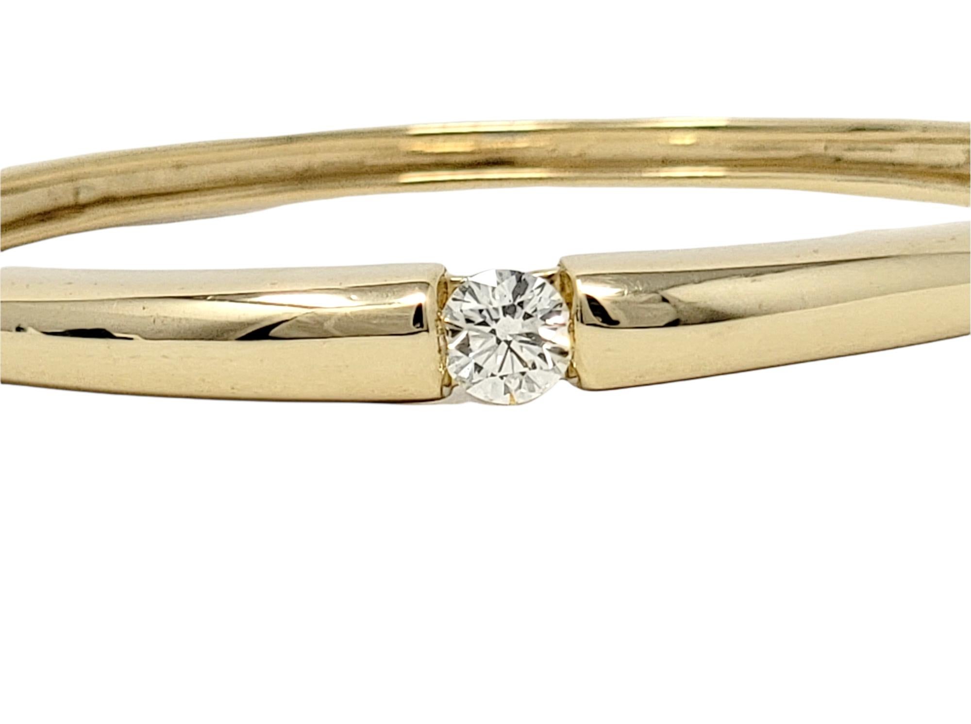 Dieses schlichte, moderne Armreifarmband ist mühelos elegant und absolut hinreißend. Mit poliertem Gelbgold und einem einzelnen Solitärdiamanten in der Mitte ist diese moderne Schönheit schlicht genug für den Alltag, aber auch besonders genug für