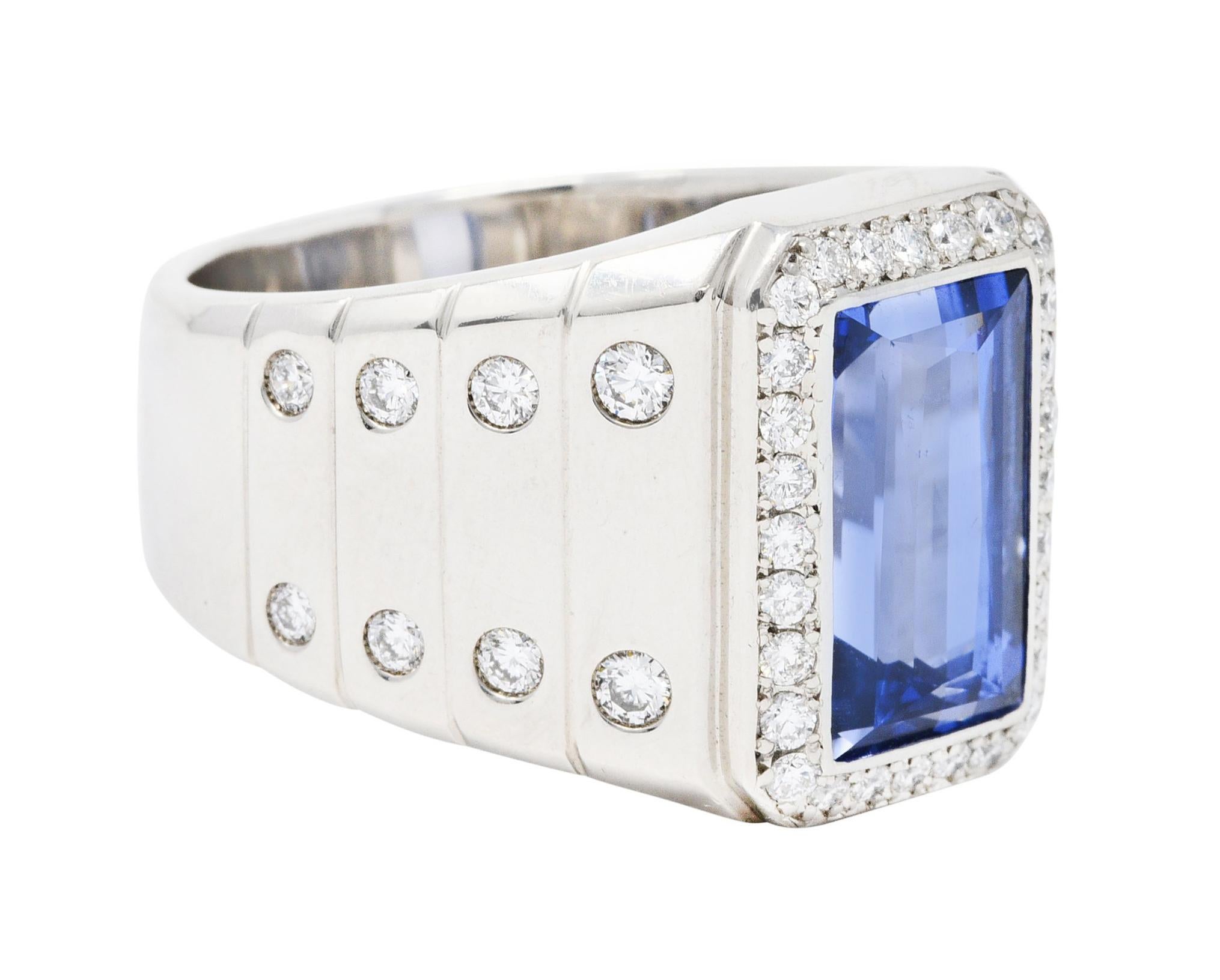 Wide band ring centers a rectangular cut sapphire weighing 6.45 carats

Transparent with vibrant and uniform violetish blue color - bezel set

Surrounded by a diamond halo and flanked by diamond accents - flush set in link motif shoulders

Weighing