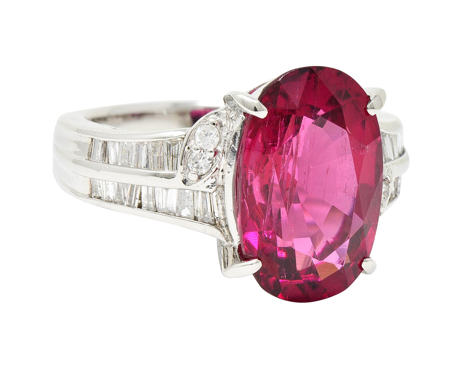 Featuring an oval cut rubellite tourmaline weighing 6.97 carats

Transparent with natural inclusions with strongly pinkish red in color

Talon set and flanked by channel set shoulders with a leaf motif

With tapered baguette and round brilliant cut