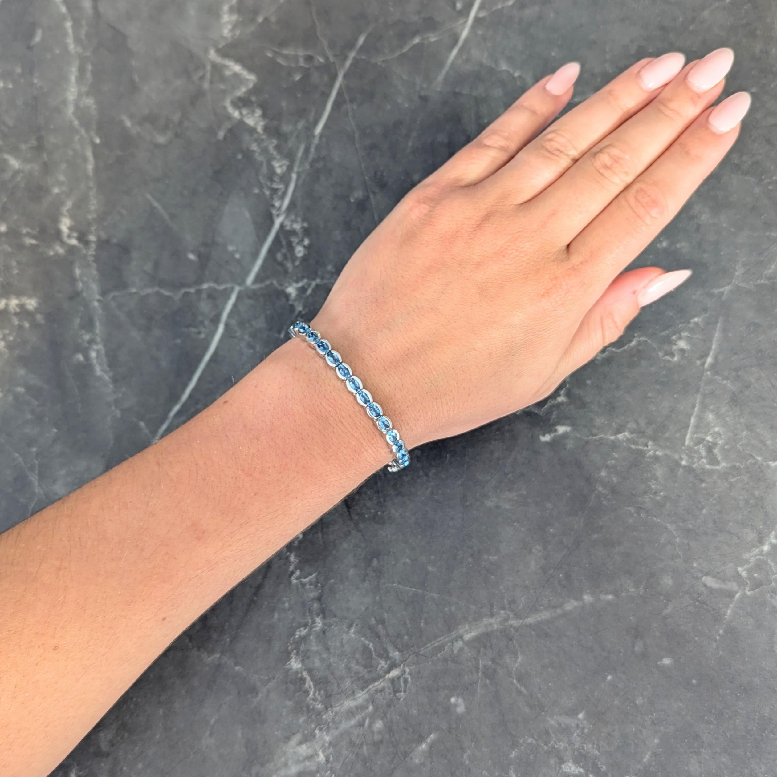 Comprised of hinged oval links bar set with oval cut topaz
Weighing approximately 9.80 carats total
Transparent bright medium blue in color
Completed by concealed clasp closure
With hinged bar and figure eight safety
Stamped for 14 karat gold
With