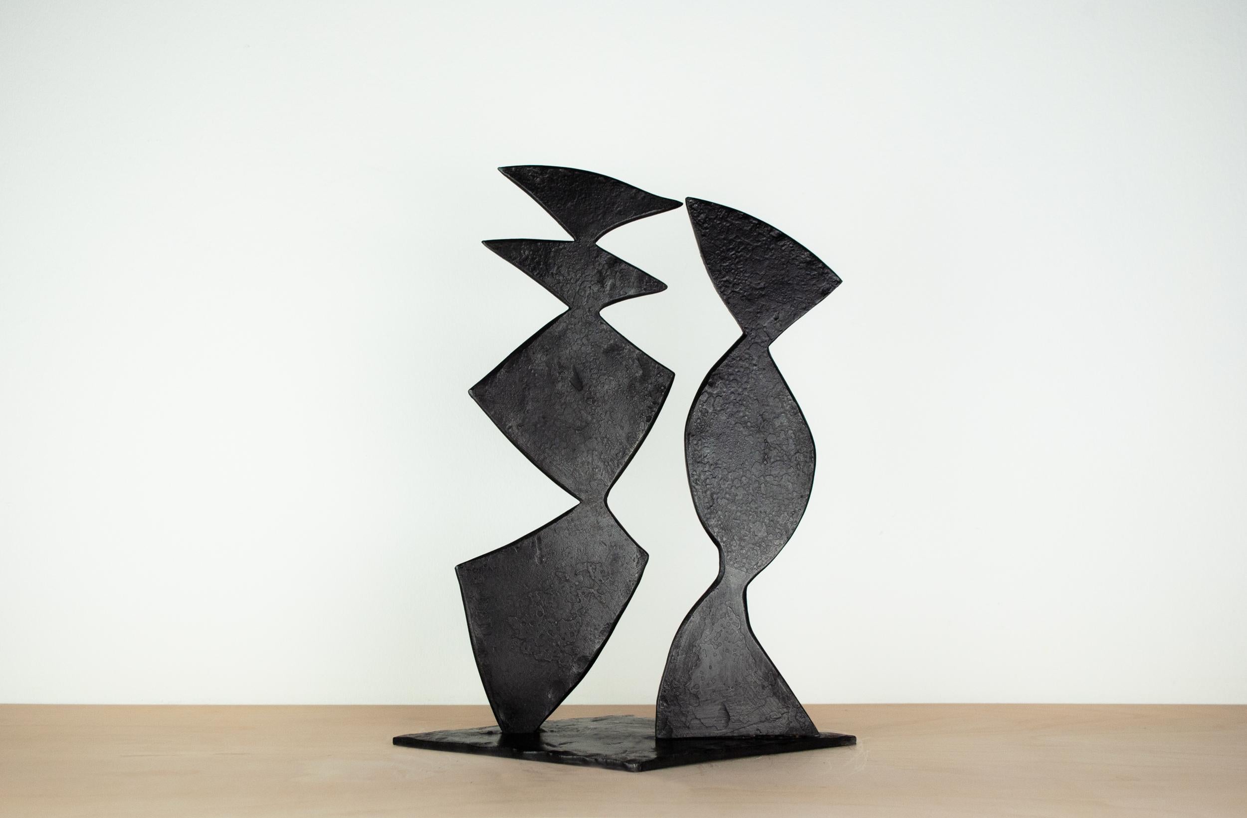 Sculpture abstraite en acier forgé noir. Composition de deux formes abstraites reposant sur une base en forme de diamant. Les formes sont inclinées les unes par rapport aux autres pour exprimer une relation tridimensionnelle. Les deux formes créent