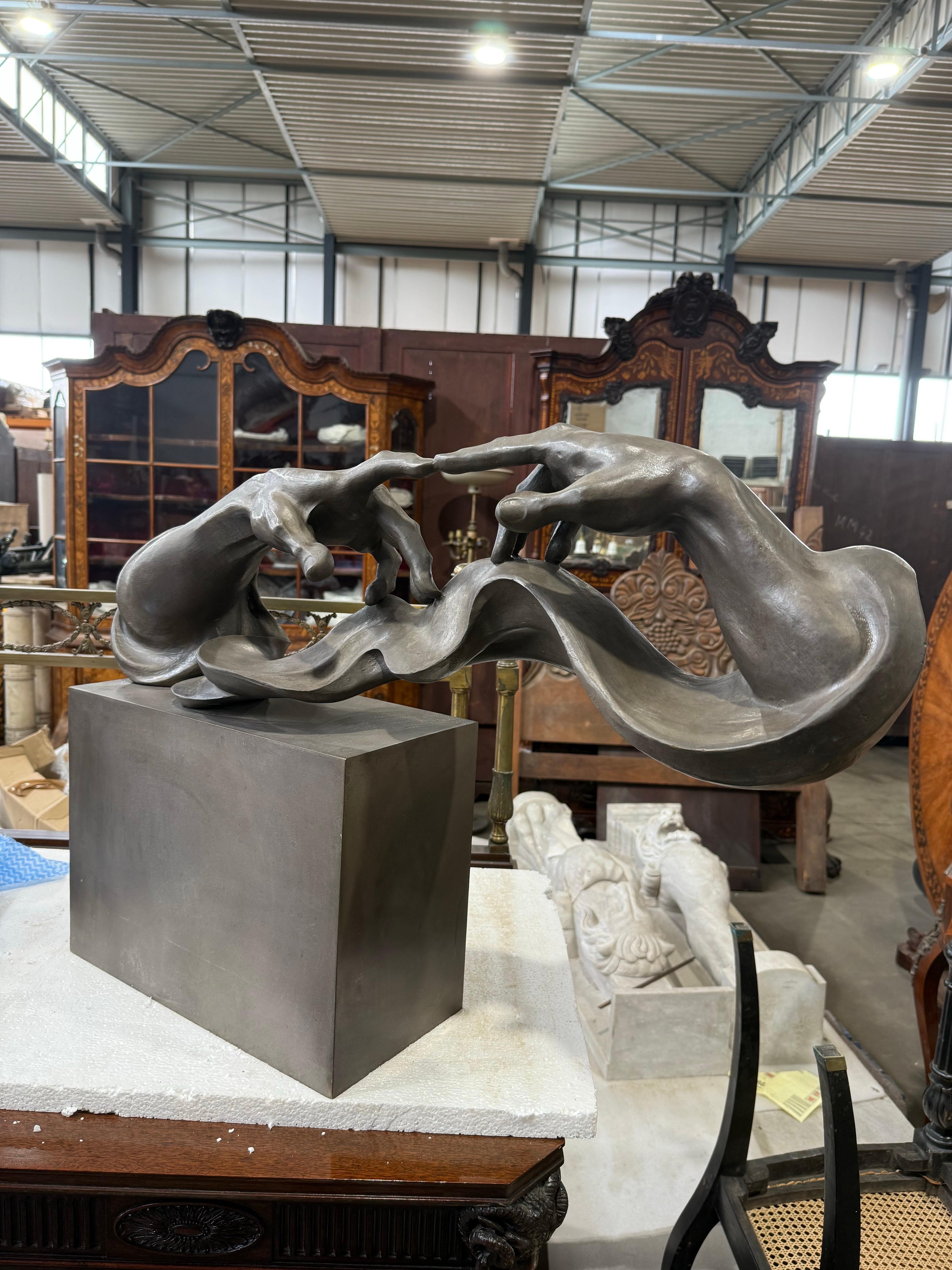 Una llamativa escultura moderna de bronce que capta una interpretación fluida y surrealista de la conexión humana, con un par de manos alargadas y entrelazadas representadas en una abstracción dinámica. Haciéndose eco del gesto icónico de la
