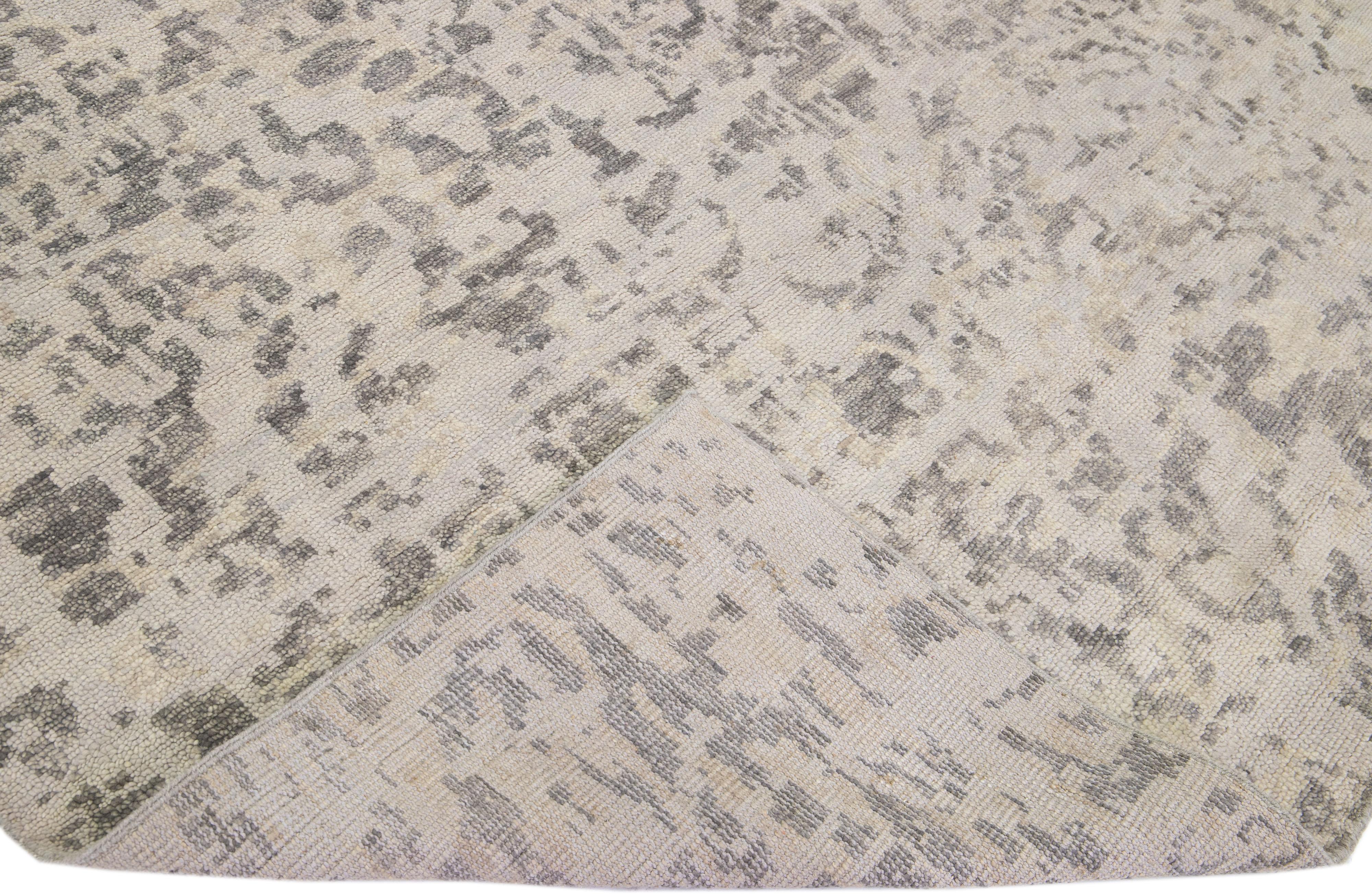 Schöne zeitgenössische Teppiche von Thom Filicia Home Collection. Dieser indische handgeknüpfte Teppich aus Wolle hat ein grau-beiges Feld und dunkelgraue Akzente im gesamten Design. 
Thom Filicias Auge für exquisite Details und schöne Texturen