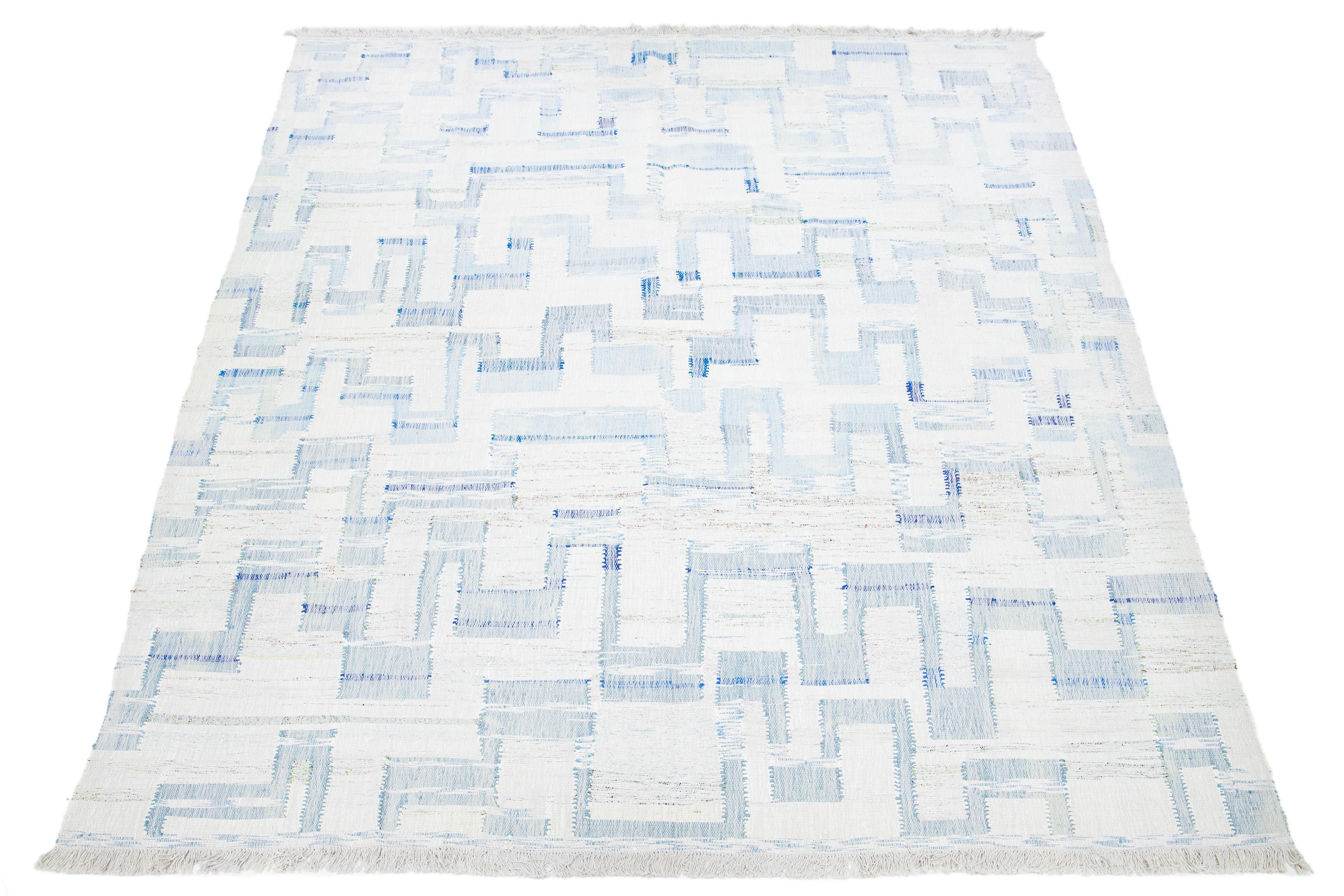 Dieser Teppich zeichnet sich durch ein modernes Kelim-Flachgewebe aus Wolle mit elfenbeinfarbenem Grund und einem abstrakten blauen Motiv aus.

Dieser Teppich misst 9'9
