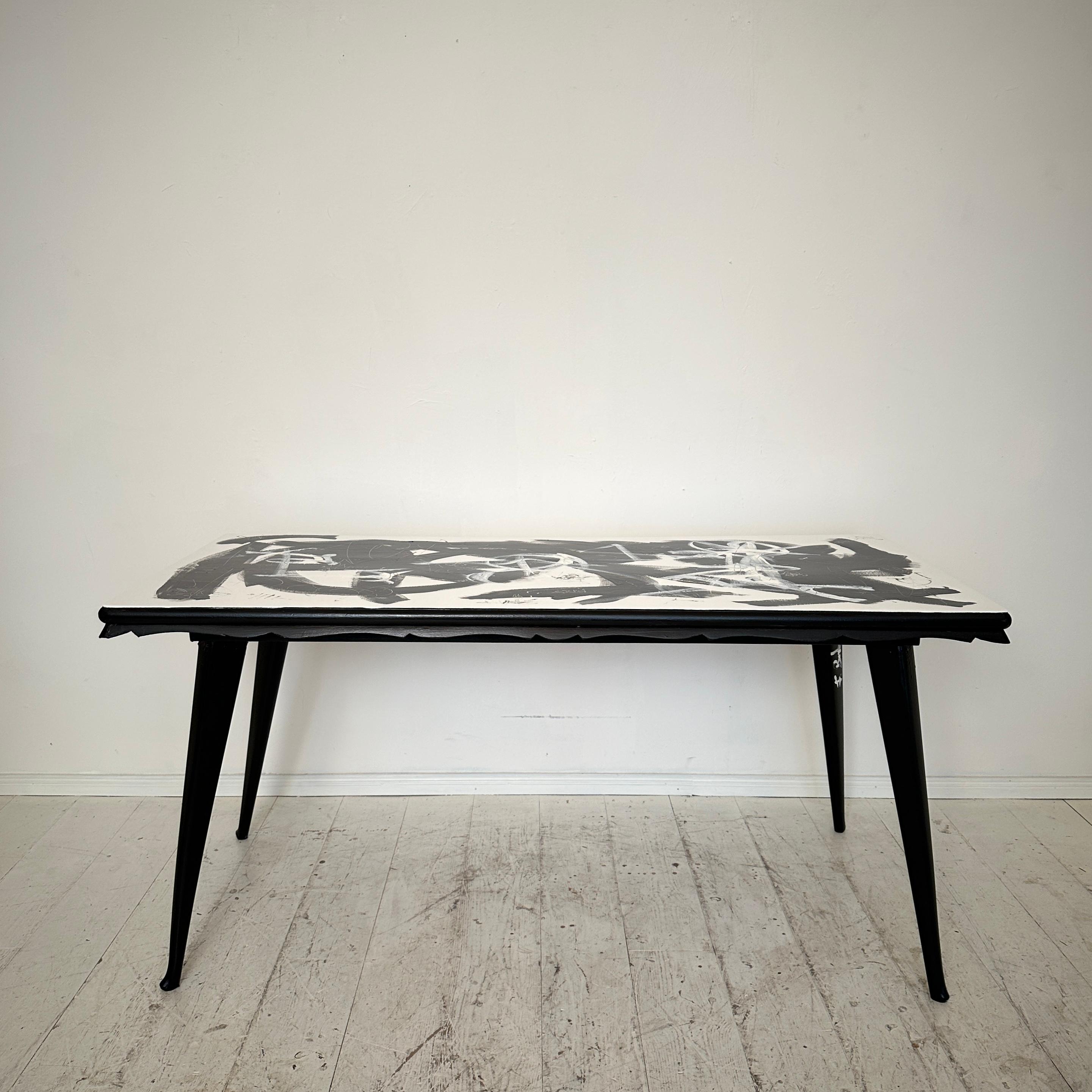 Elevate your dining experience with this striking contemporary abstract painted dining table featuring a 1950s base. The marriage of black and white hues on its surface creates a captivating visual narrative, blending modernity with timeless
